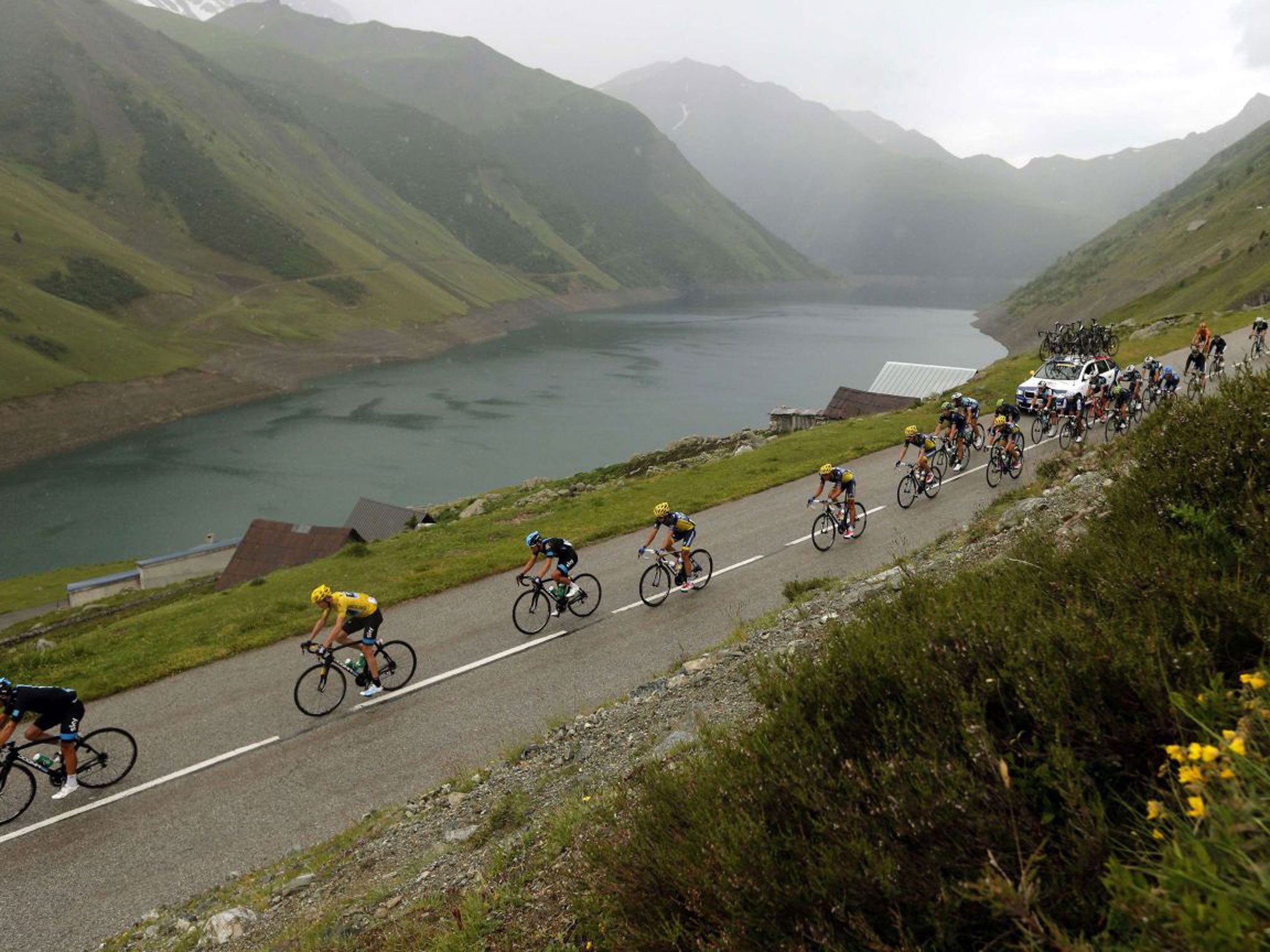 The yellow jersey of Chris Froome heads the peloton in the Alpine rain