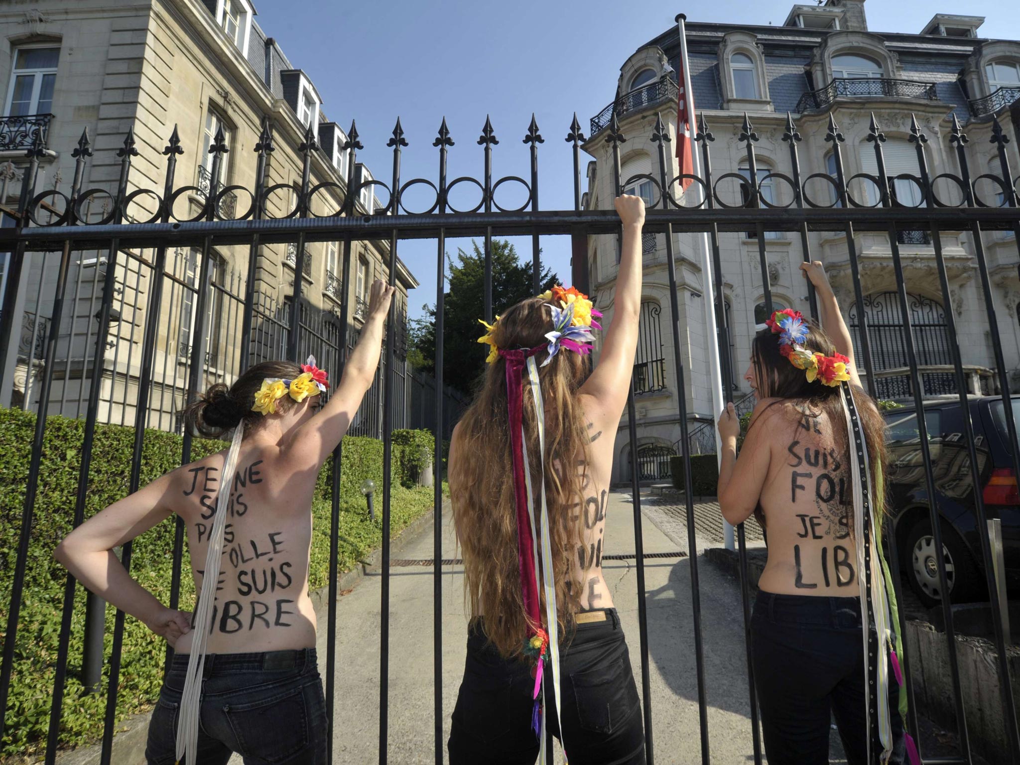 22 July 2013: Members of Femen Belgium shout slogans outside the gates of the Tunisian embassy after they used a chain to lock the gates, during a protect calling for the release of fellow activist Tunisian Amina Tyler, in Brussels