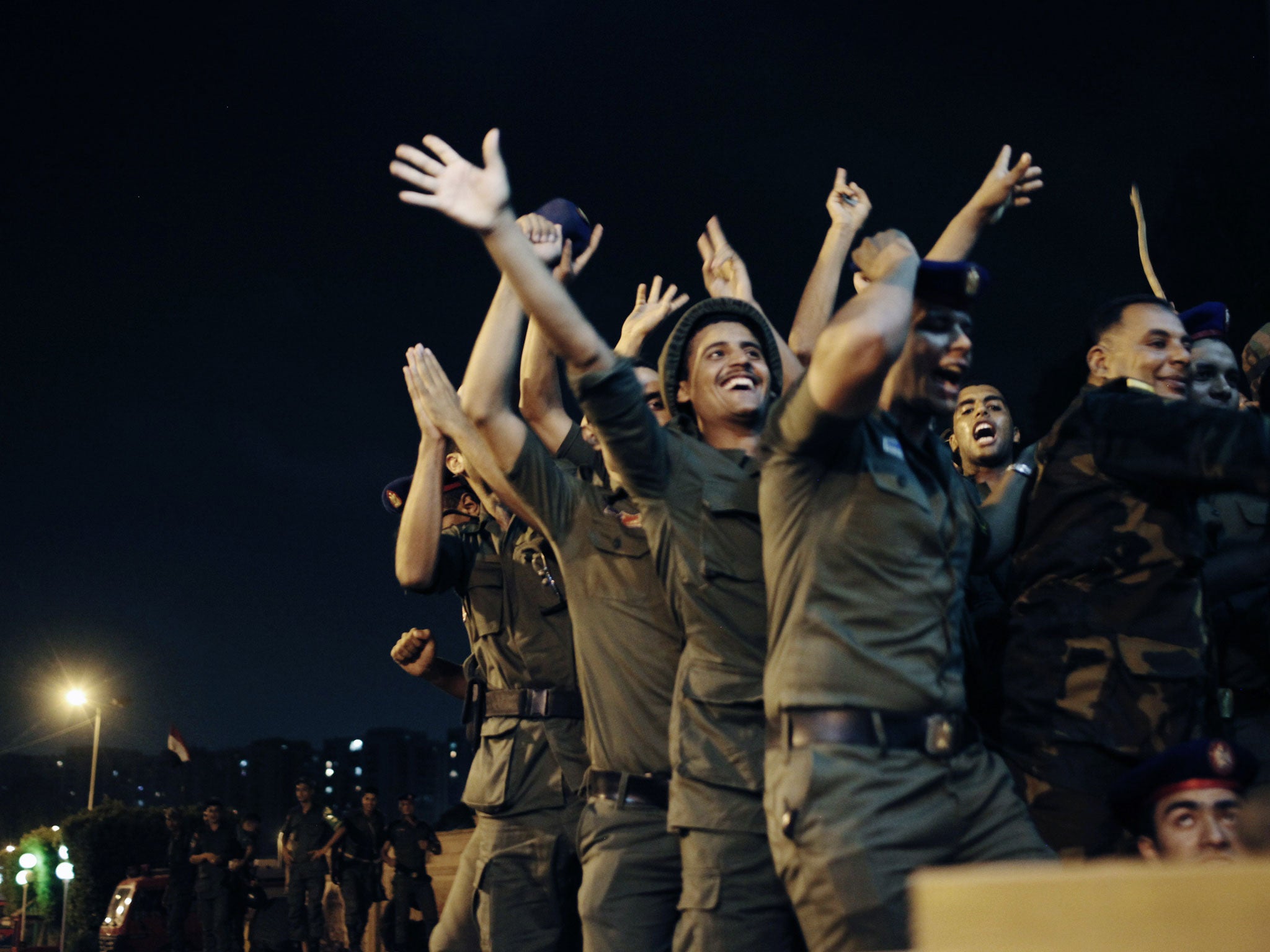 Officers of the Egyptian Republican Guard celebrate at the gates of the Republican Guard headquarters in the suburb of Nasr City after a broadcast by the head of the Egyptian military confirming that they will temporarily be taking over from the country's first democratically elected president Mohammed Morsi on July 3, 2013 in Cairo, Egypt.