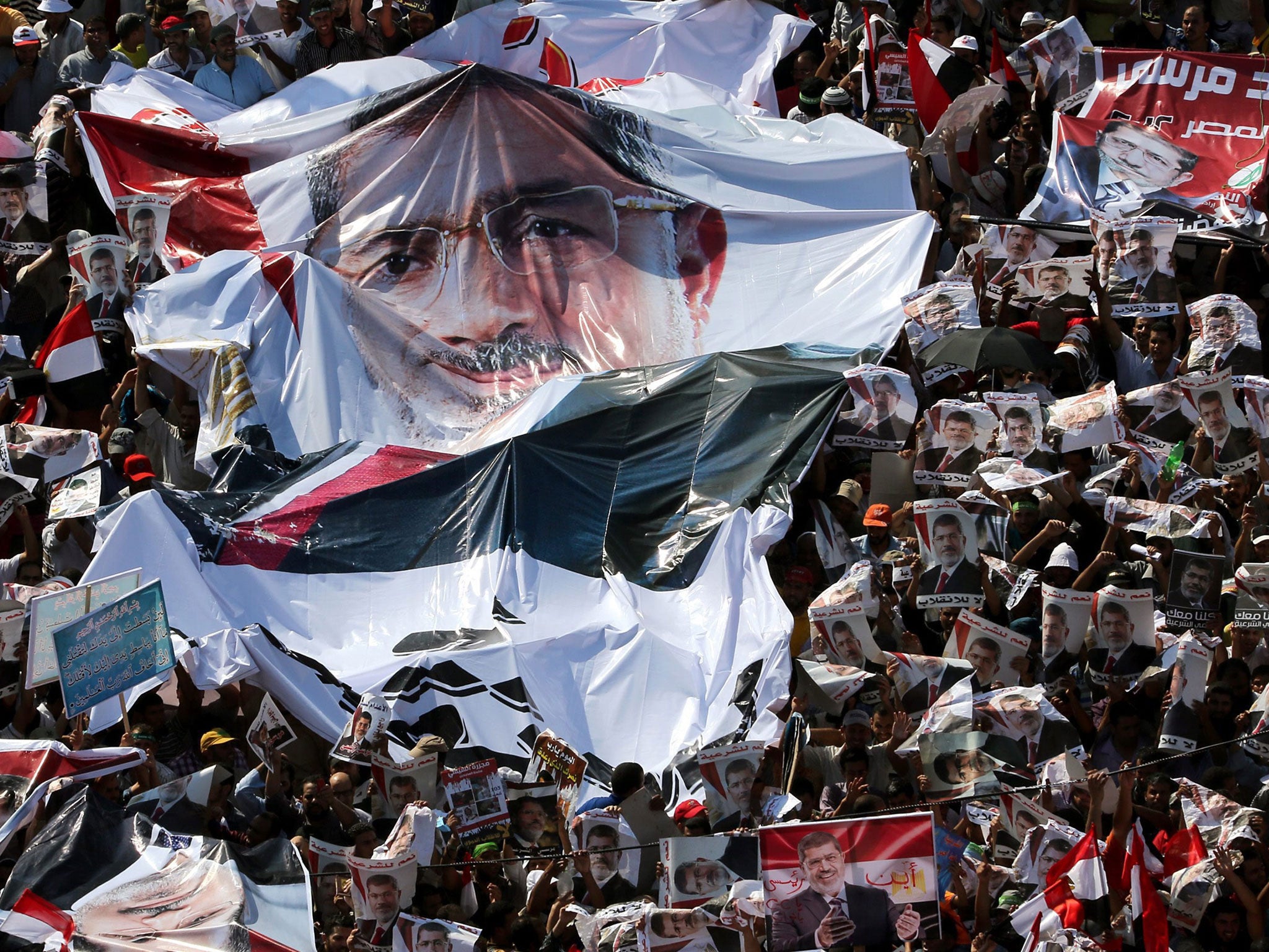 Members and brotherhood supporters of ousted president Mohamed Morsi attend a protest near Rabaa al-Adawiya mosque in Cairo