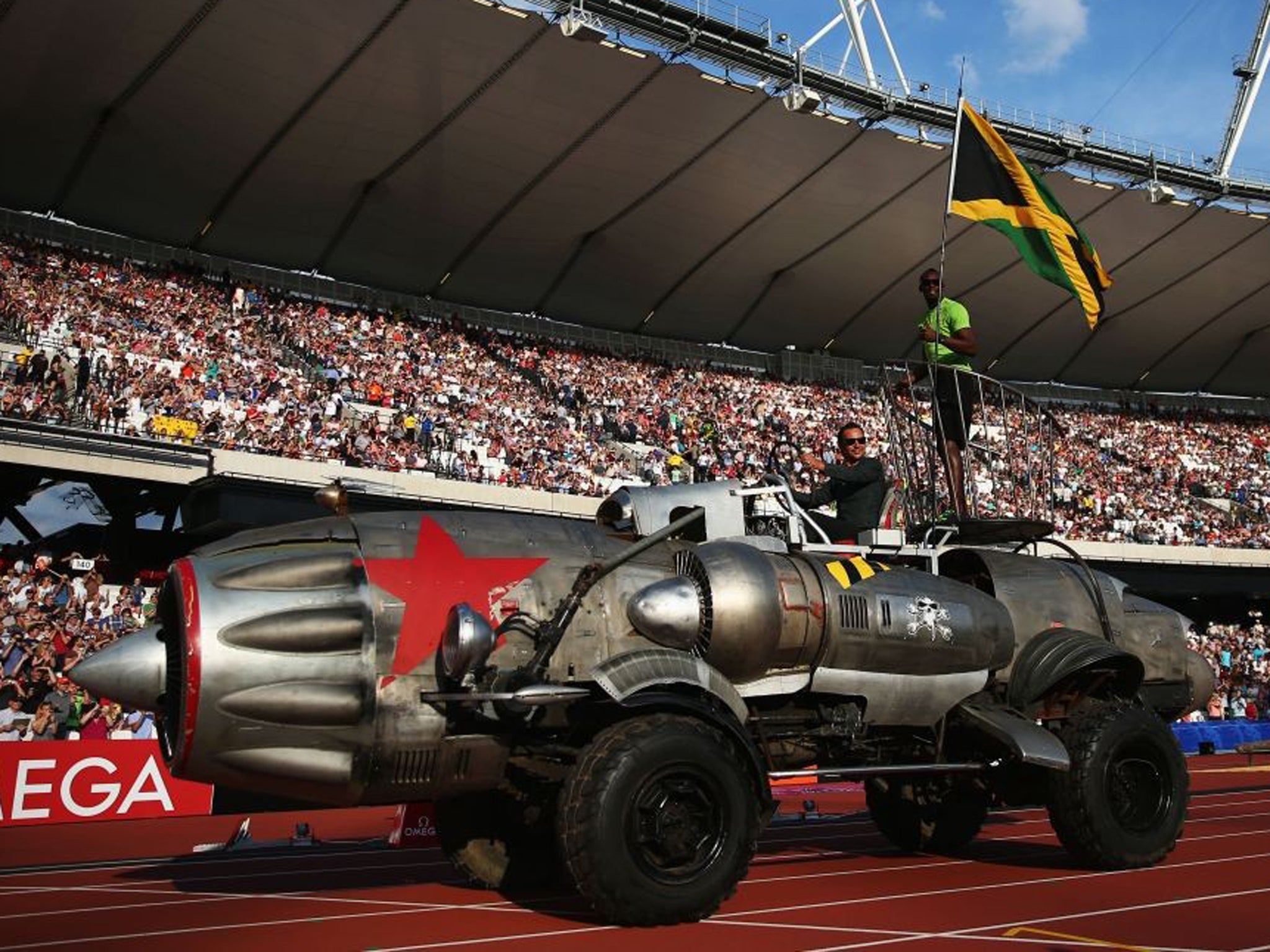 Usain Bolt with a Jamaica flag arrives in the Olympic Stadium in typically flamboyant style aboard a jet engine car