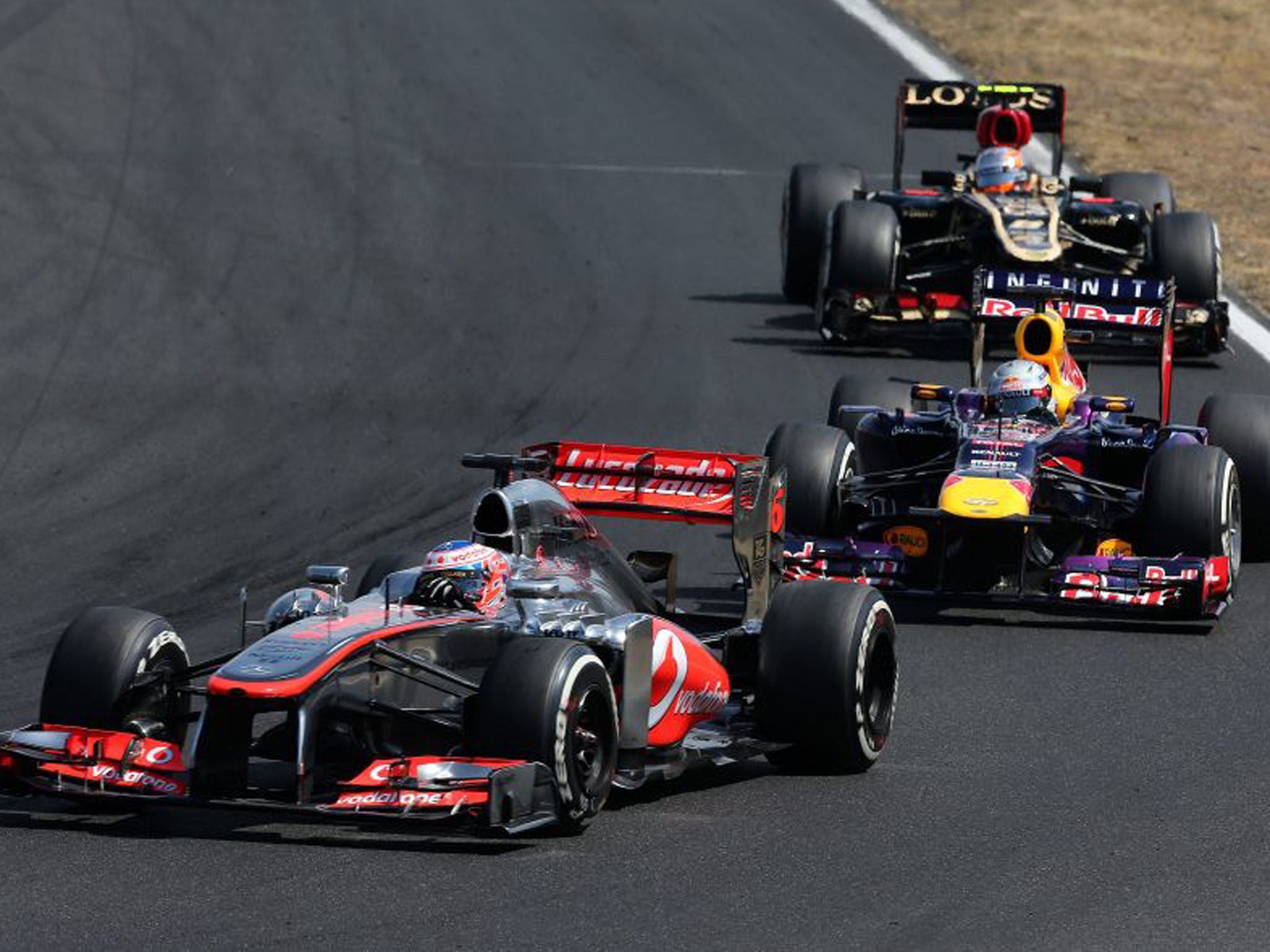 Jenson Button, front, holds off a challenge of Vettel. Having started 13 on the grid Button would finish seventh -  but he would be angered by a clash with Grosjean, back, during the race