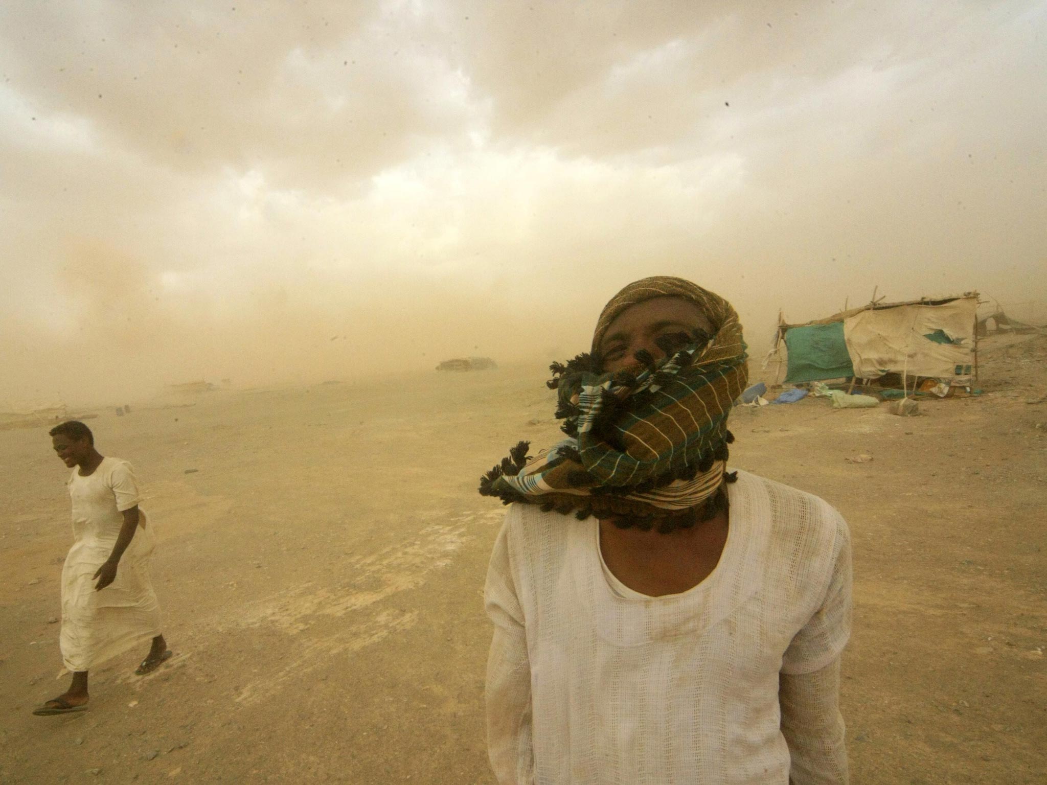 Gold mine workers walk to their shelter during a sandstorm in Al-Ibedia locality at River Nile State