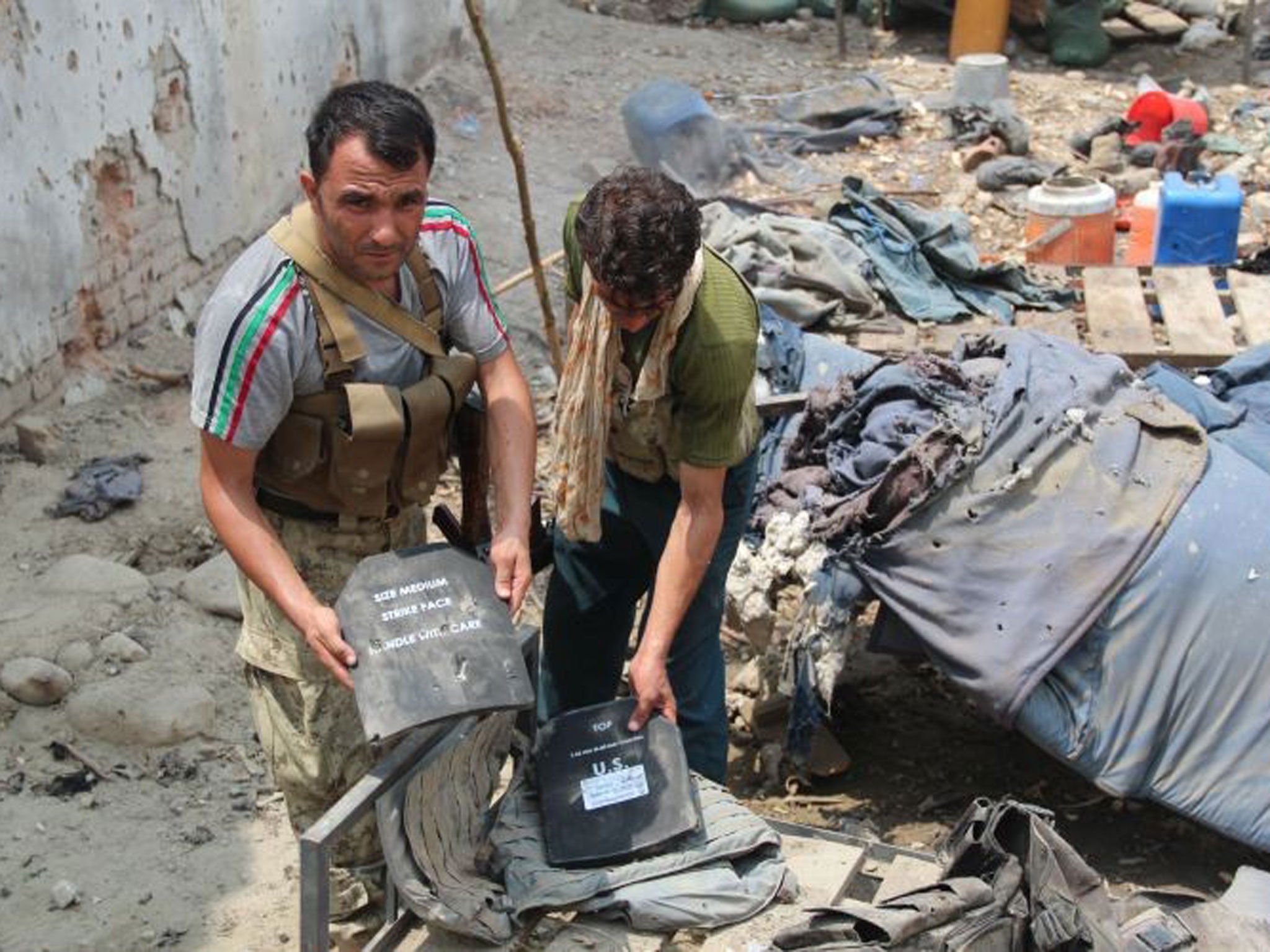 Afghan security officials investigate a police checkpoint damaged in a NATO airstrike which accidentally killed five special forces officers