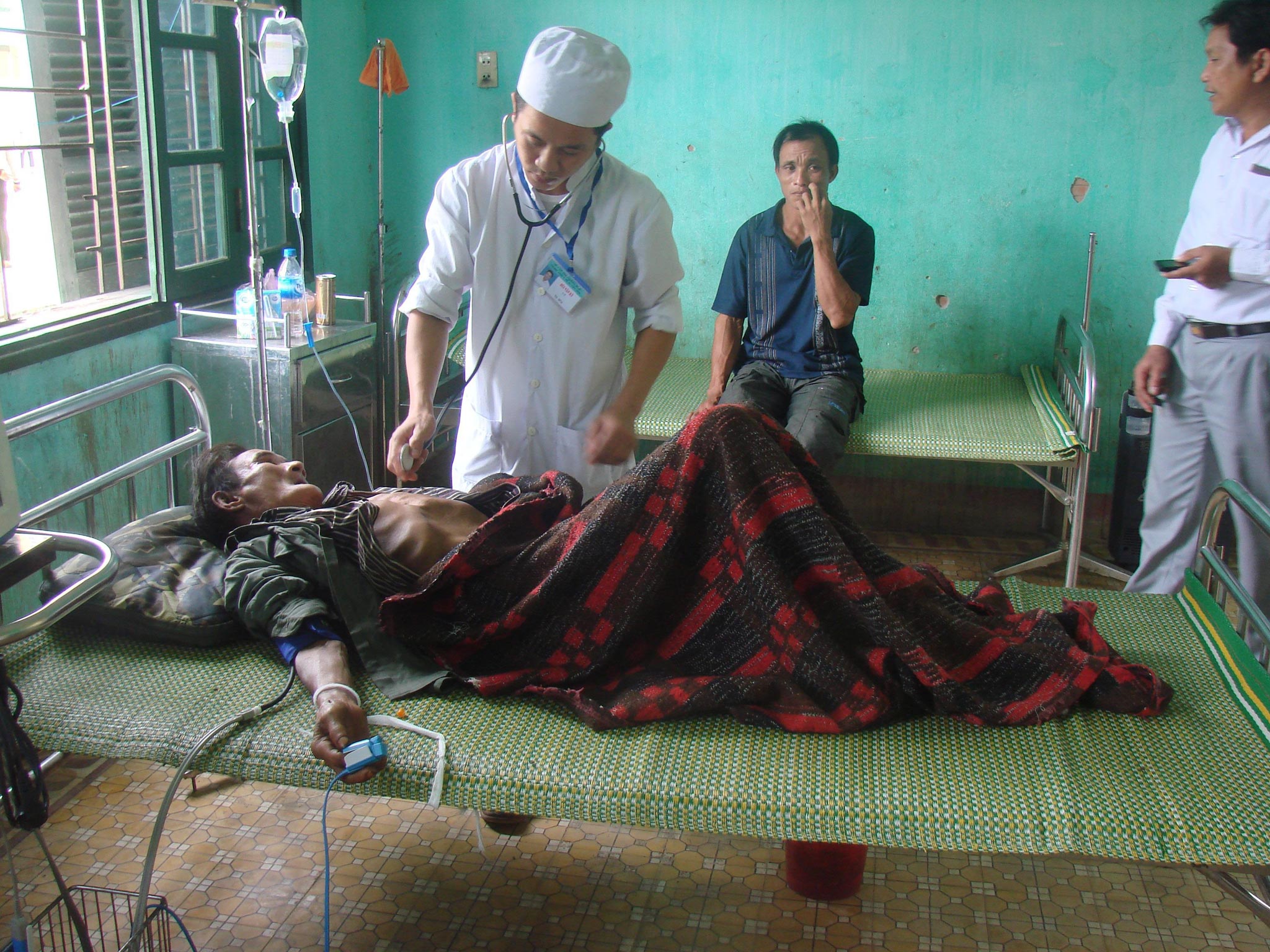 An image of 82-year-old Ho Van Thanh (left) being taken care of by a local doctor