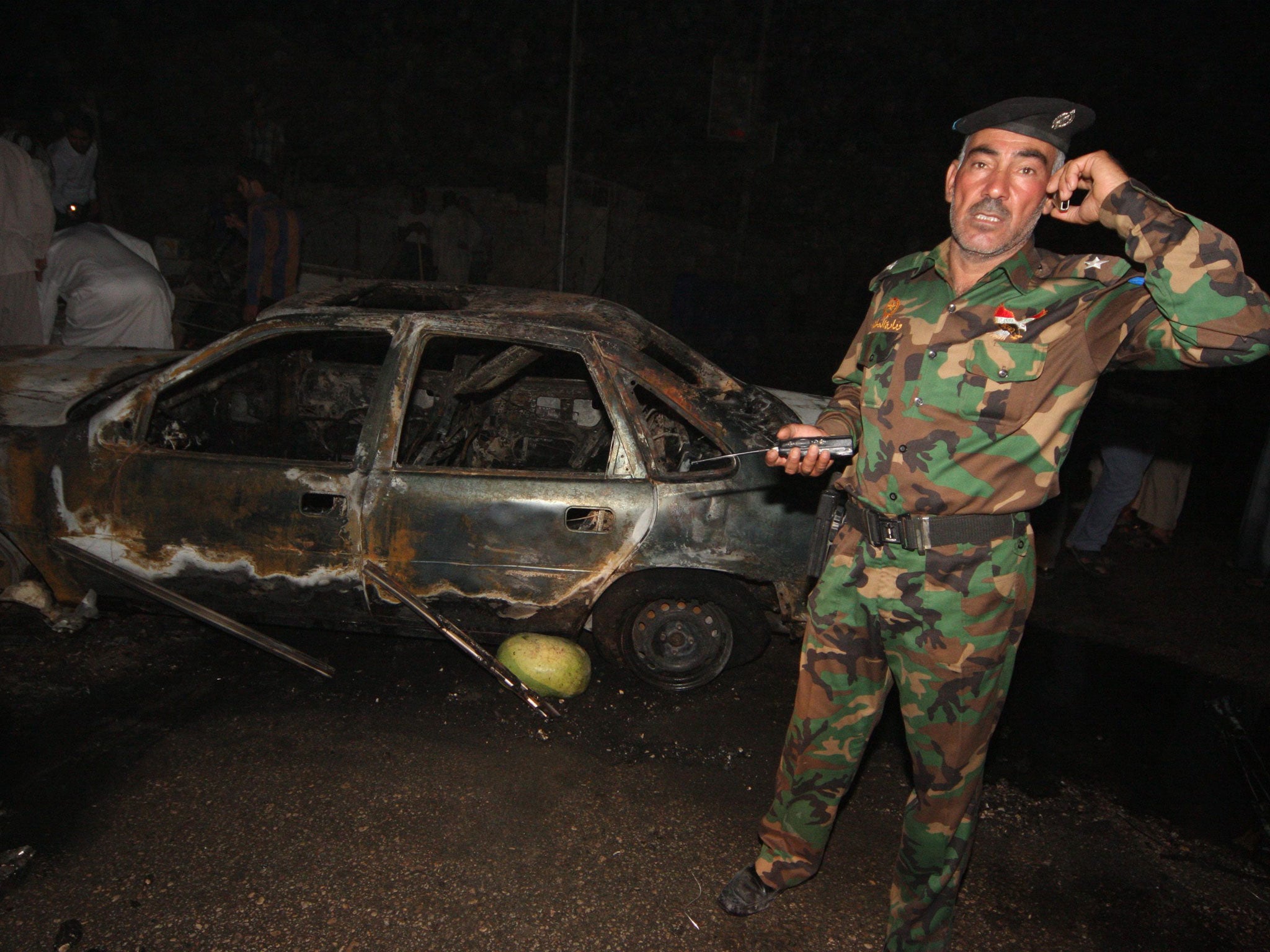 An Iraqi officer inspects the site of a car bomb near Karbala