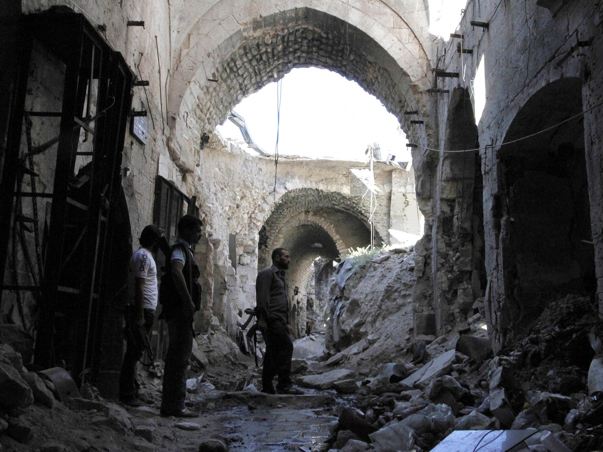 Free Syrian Army fighters walk through debris in the old city of Aleppo