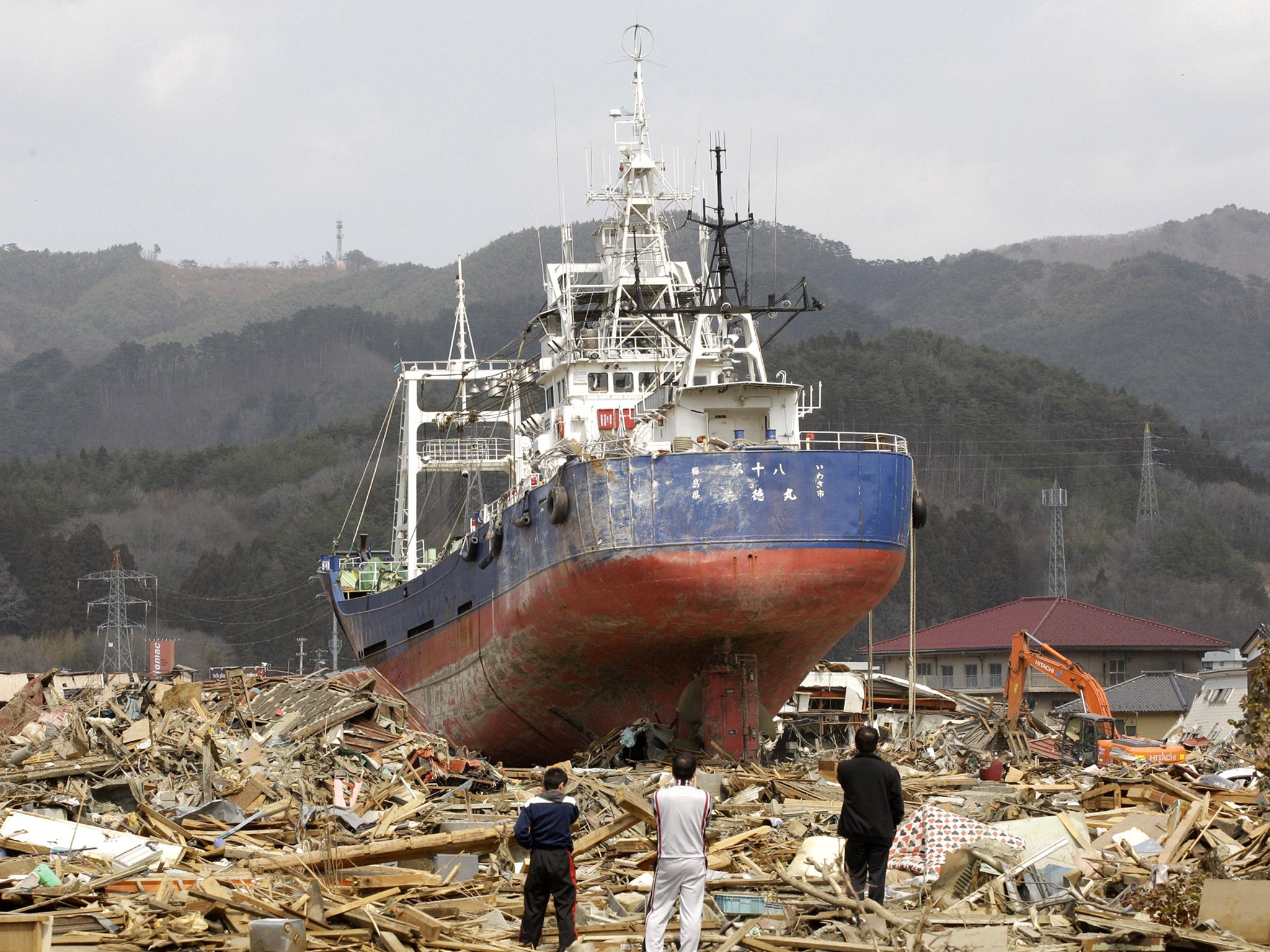 Survivors among the rubble look at the destroyed trawler after the tsunami devastated Kesennuma