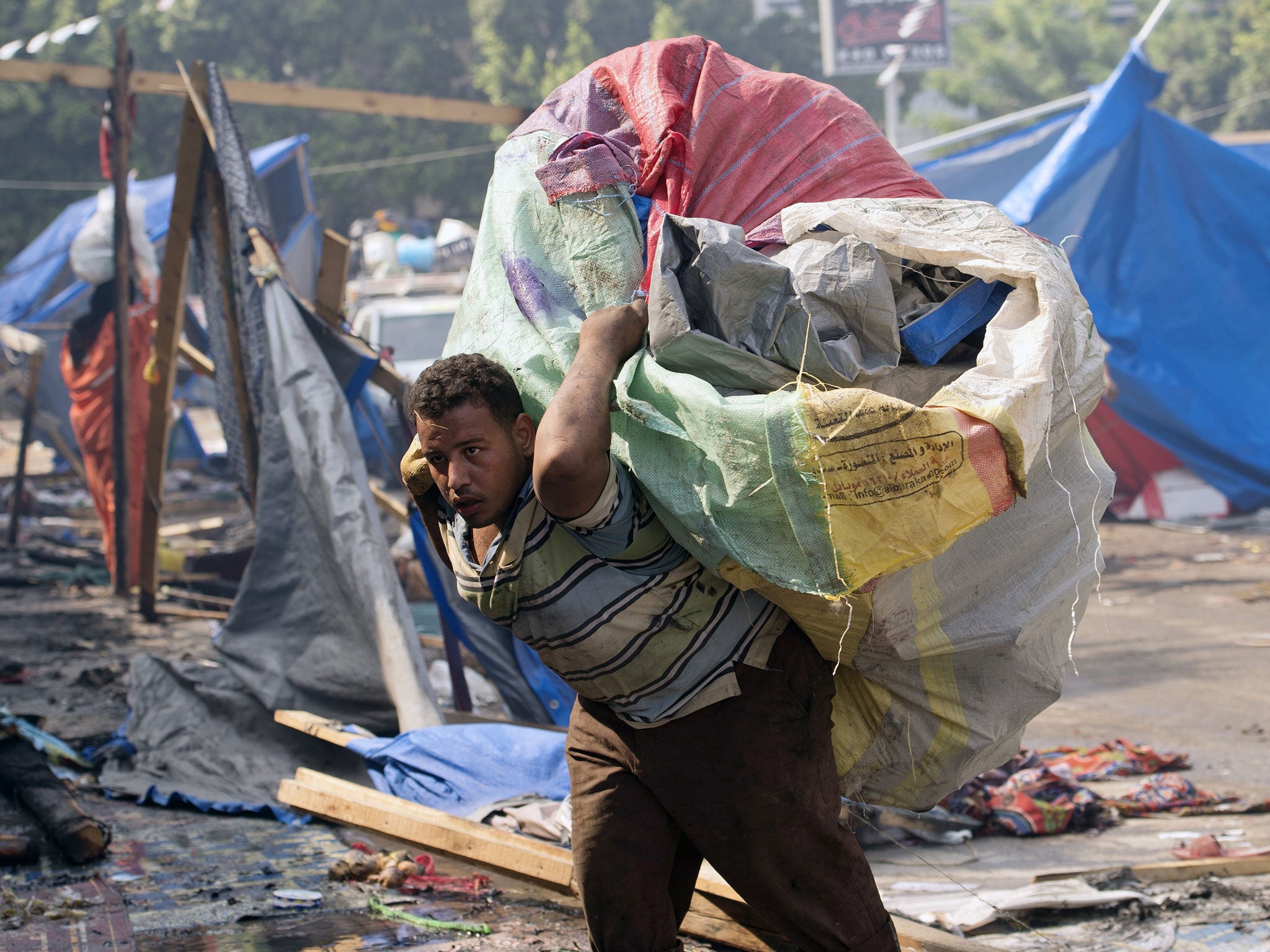 A garbage collector walks through the destroyed camp of ousted Mohammed Morsi supporters outside Rabaa al-Adawiya mosque on August 15, 2013 in Cairo, Egypt.