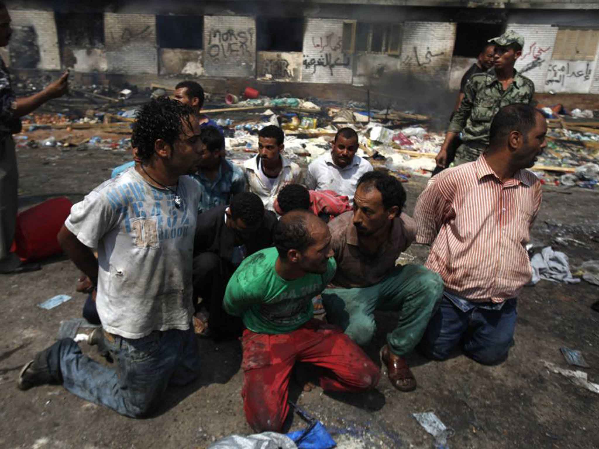 Protesters are rounded up near a burnt mosque building