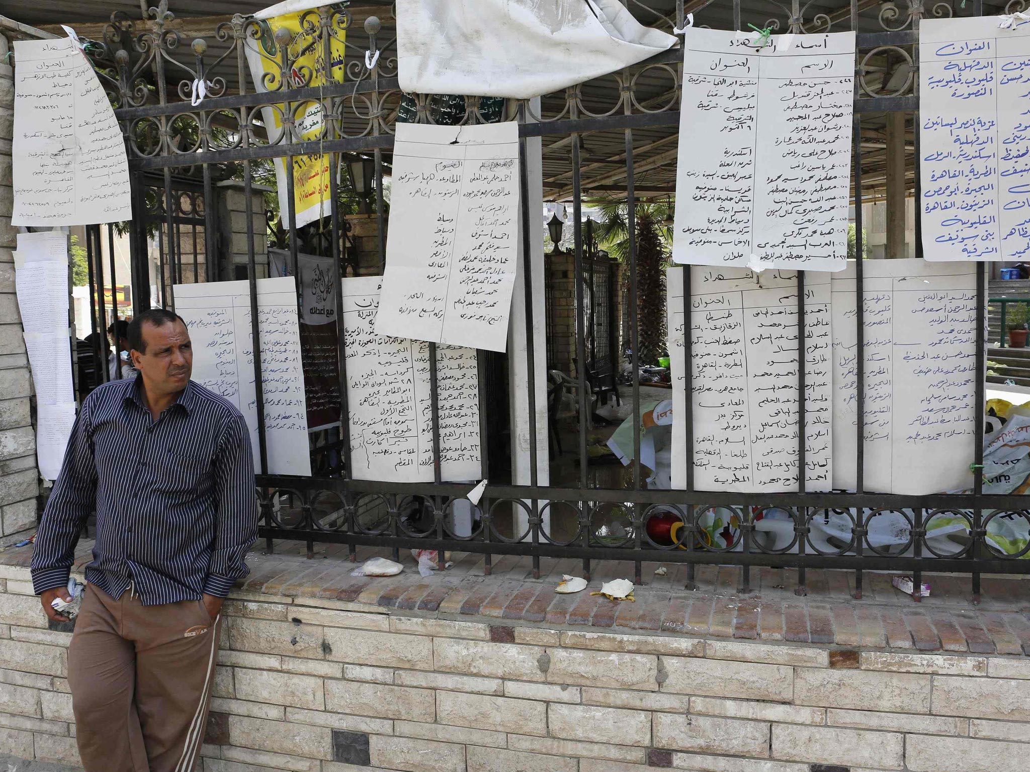 A man who lost relatives in recent violence stands near a list of names of dead members of the Muslim Brotherhood and supporters of deposed Egyptian President Mohamed Mursi at El Eyman mosque in Cairo