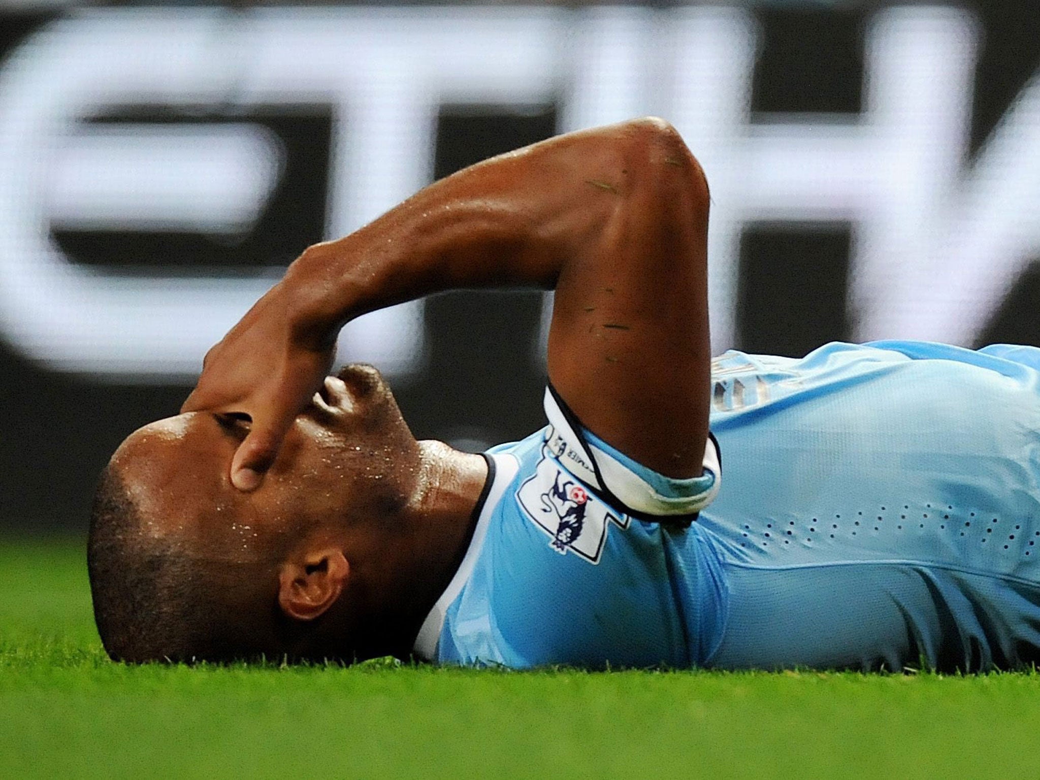 Vincent Kompany holds his head after picking up an injury after tackling Newcastle United's Sammy Ameobi