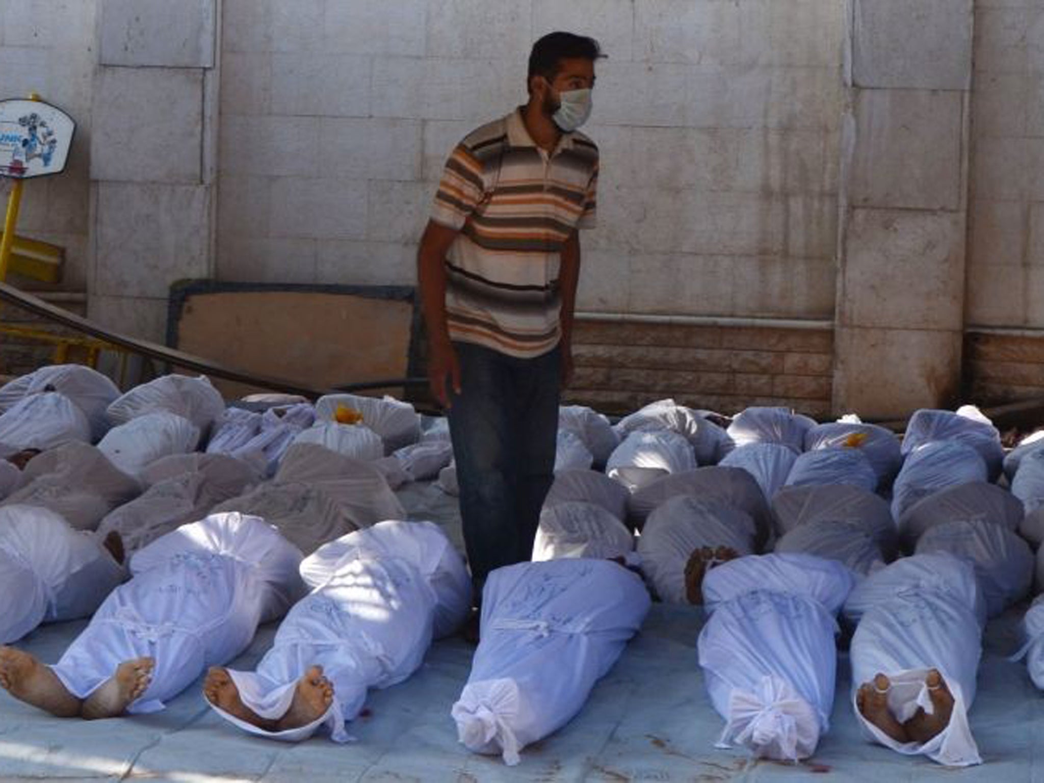 Syrian activists inspect the bodies of people they say were killed by nerve gas in the Ghouta region in 2013