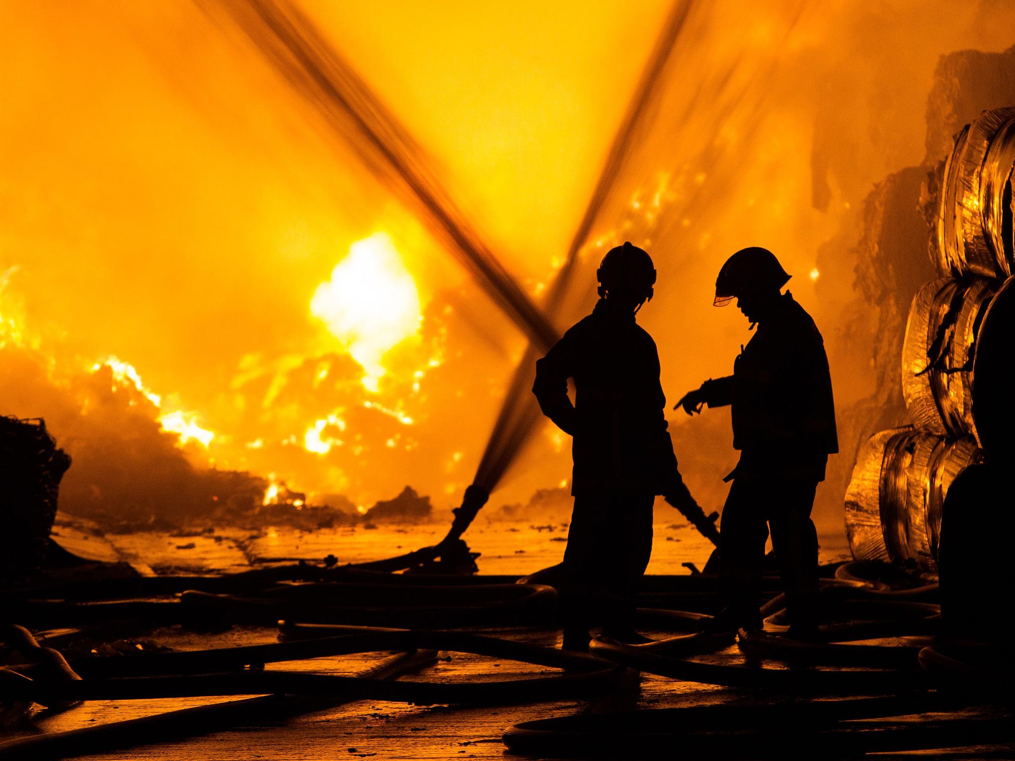 A shot of two firemen tackling a blaze at Bredbury Recycling plant in Stockport