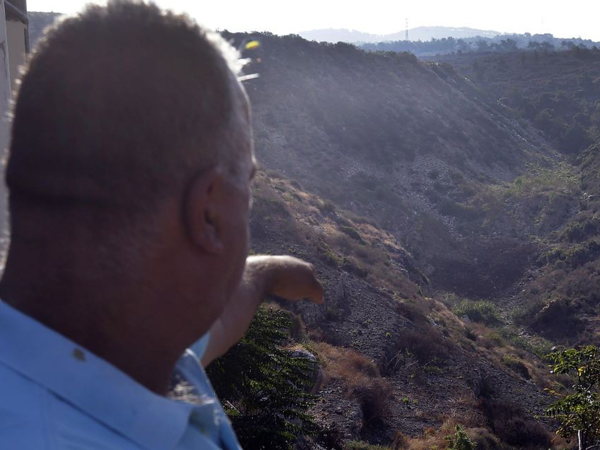 A Lebanese man, points to a missile crater, where Israeli warplanes attacked one of the entrance tunnels of the Palestinian Popular Front for the Liberation of Palestine-General Command base, near the Mediterranean coastal town of Naameh