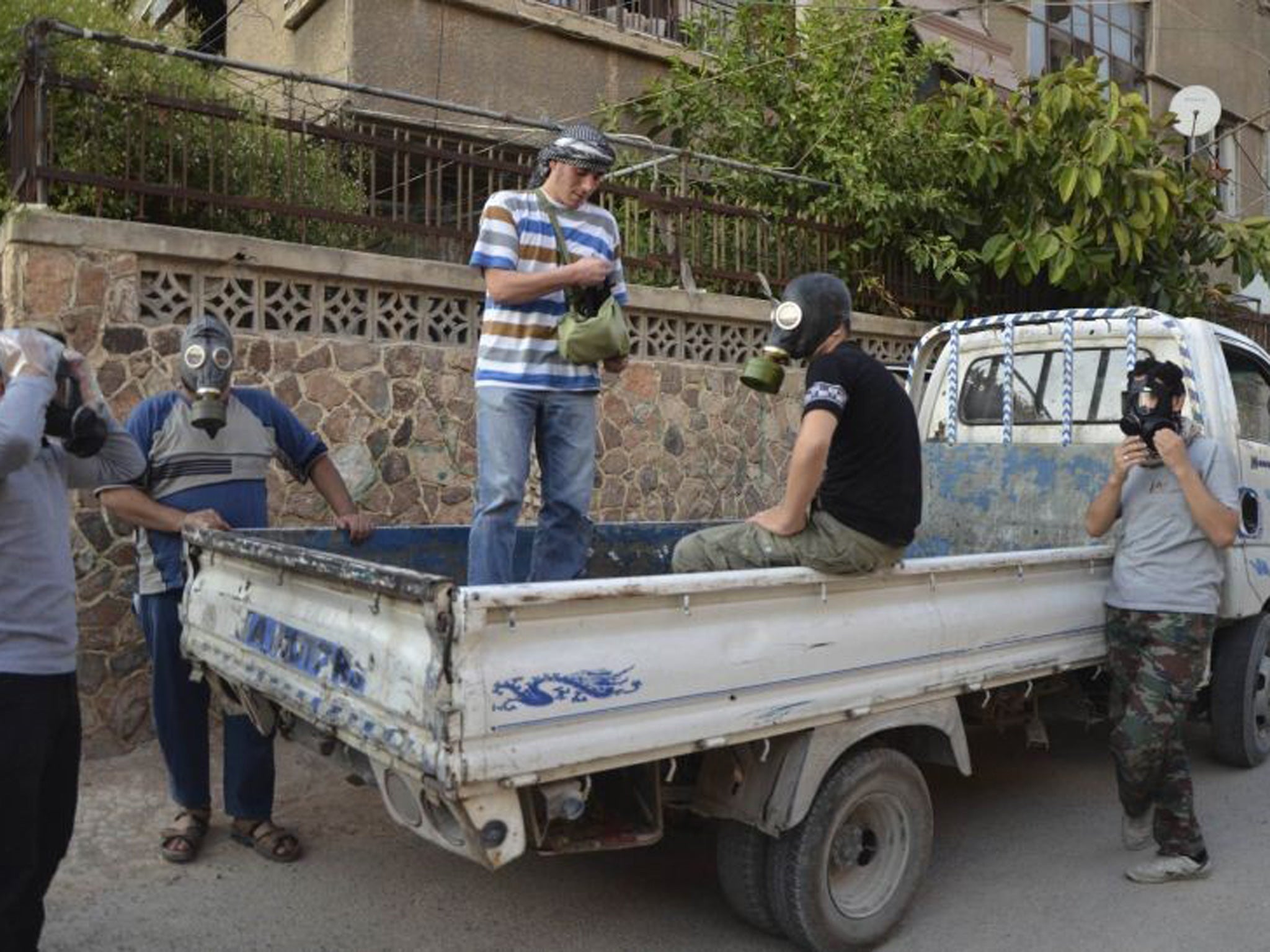 Activists wear gas masks as they look for dead bodies and collect samples to check for chemical weapon use in the Zamalka area