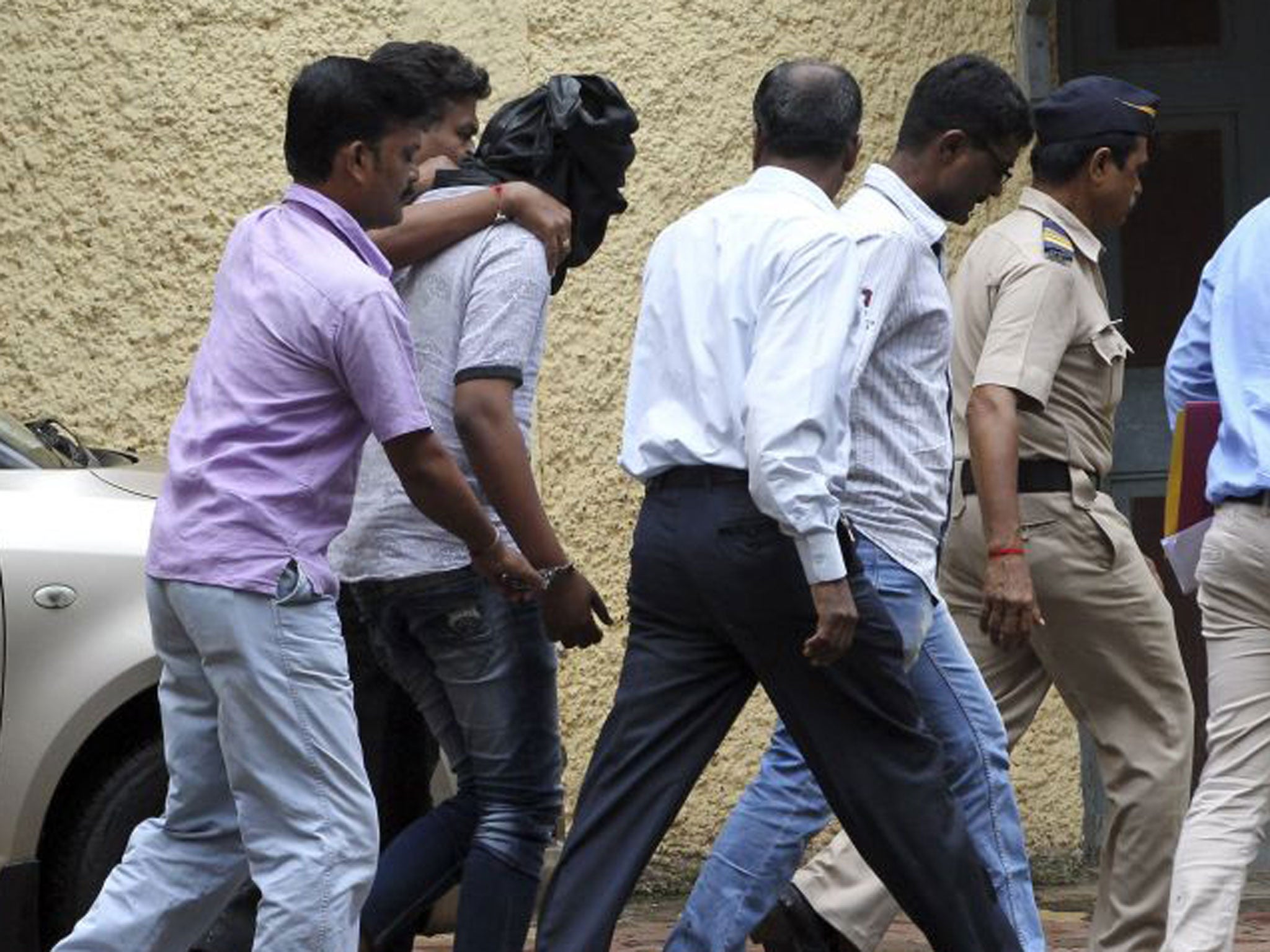 Police officials escort an accused, head covered with black cloth, in the gang rape of a young photojournalist in Mumbai