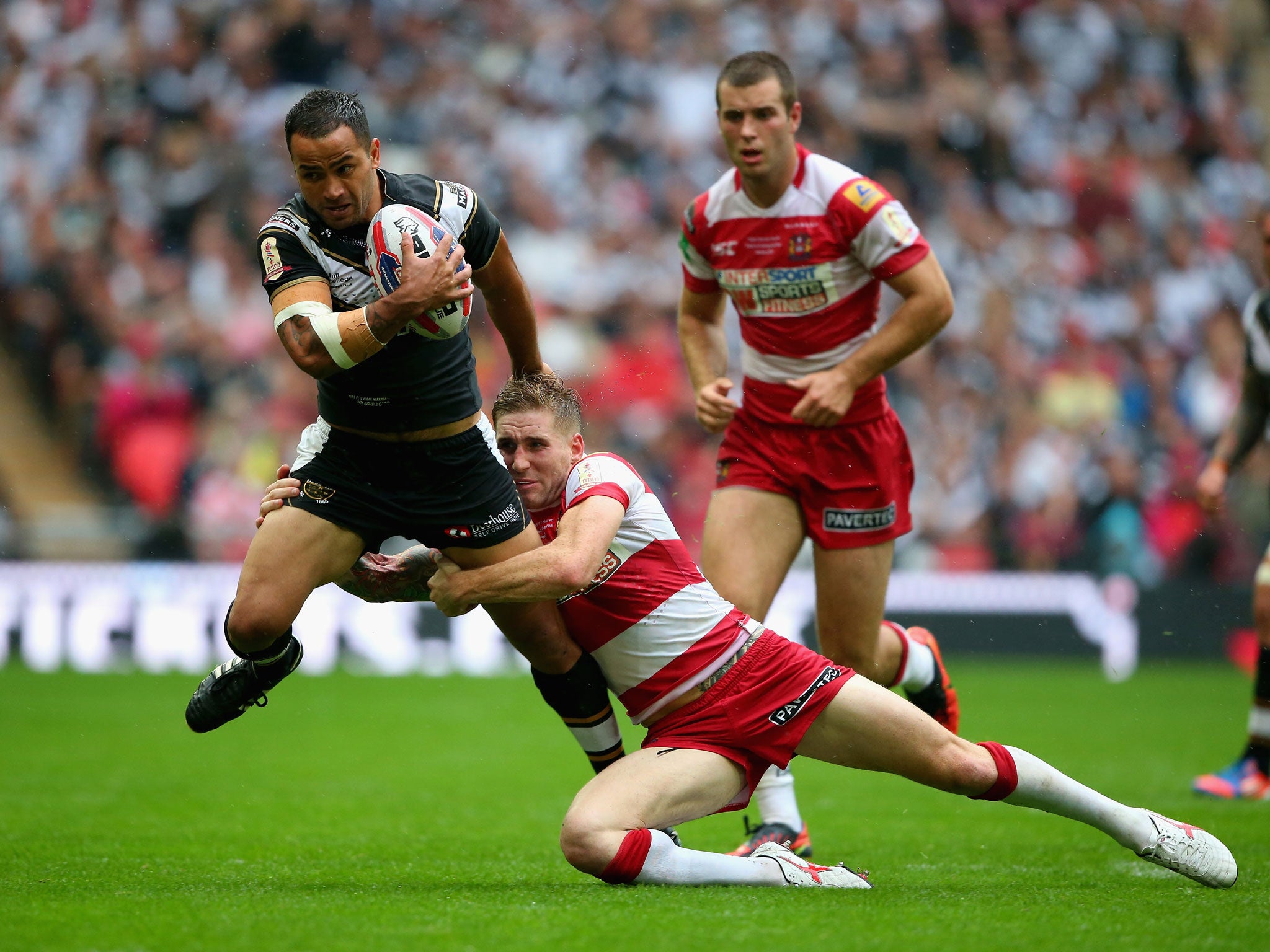 Sam Tomkins of Wigan Warriors tackles Aaron Heremaia of Hull FC