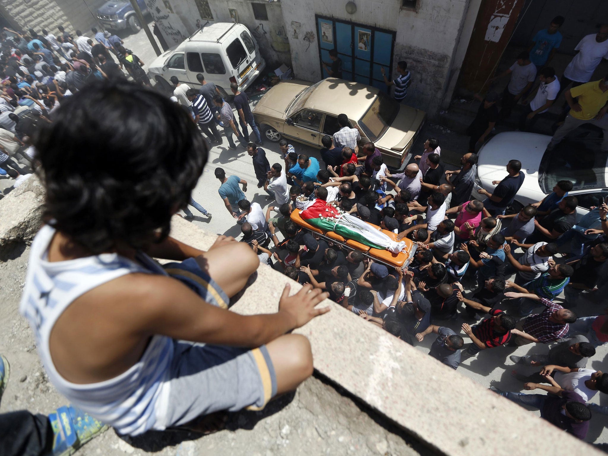 A Palestinian boy watches the funeral of Robin Zayed, Younis Jahjouh and Jihad Aslan at Qalandiya Refugee Camp near the West Bank city of Ramallah