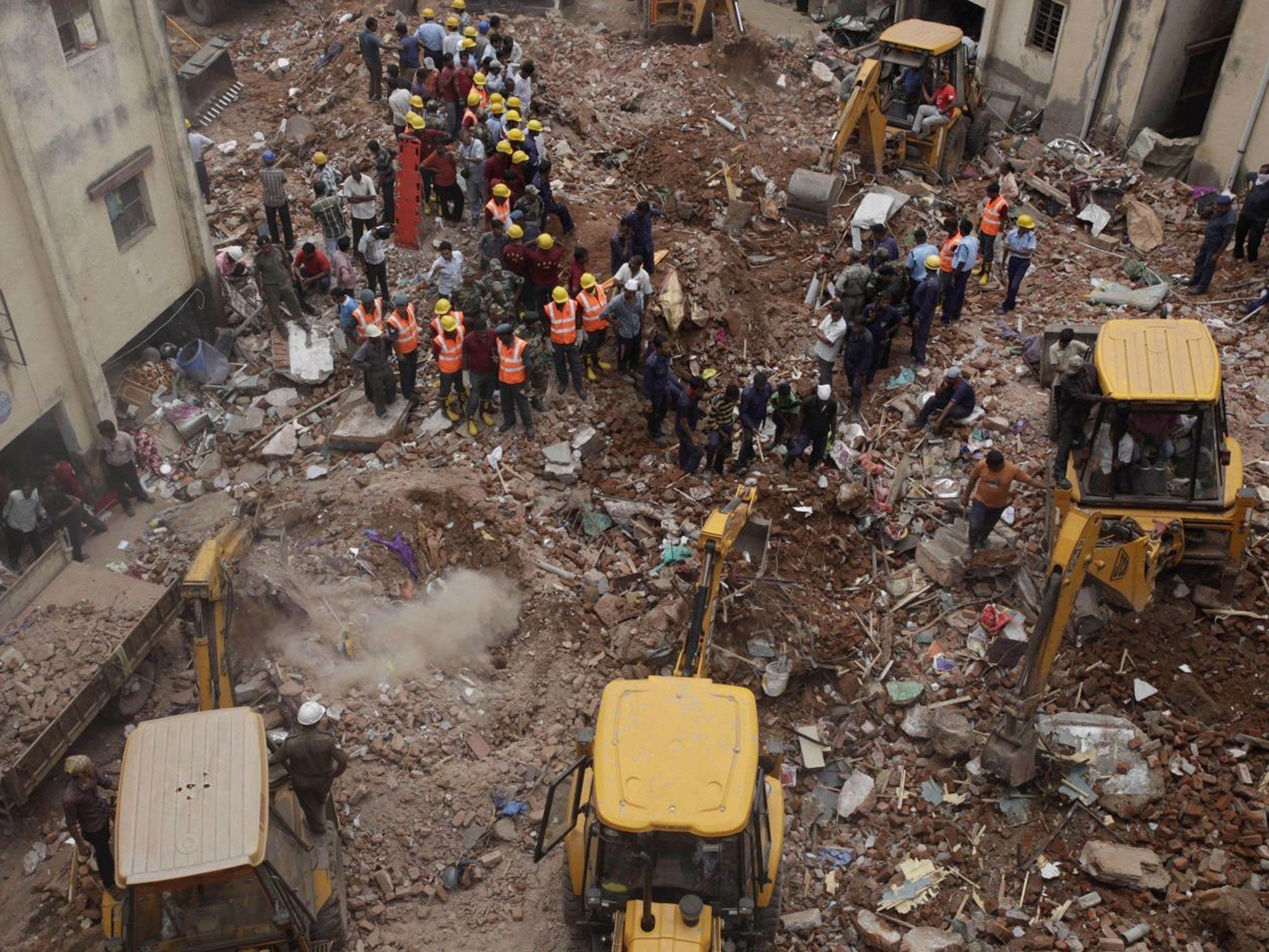 Indian rescuers use machinery to remove the debris after two adjacent apartment buildings collapsed