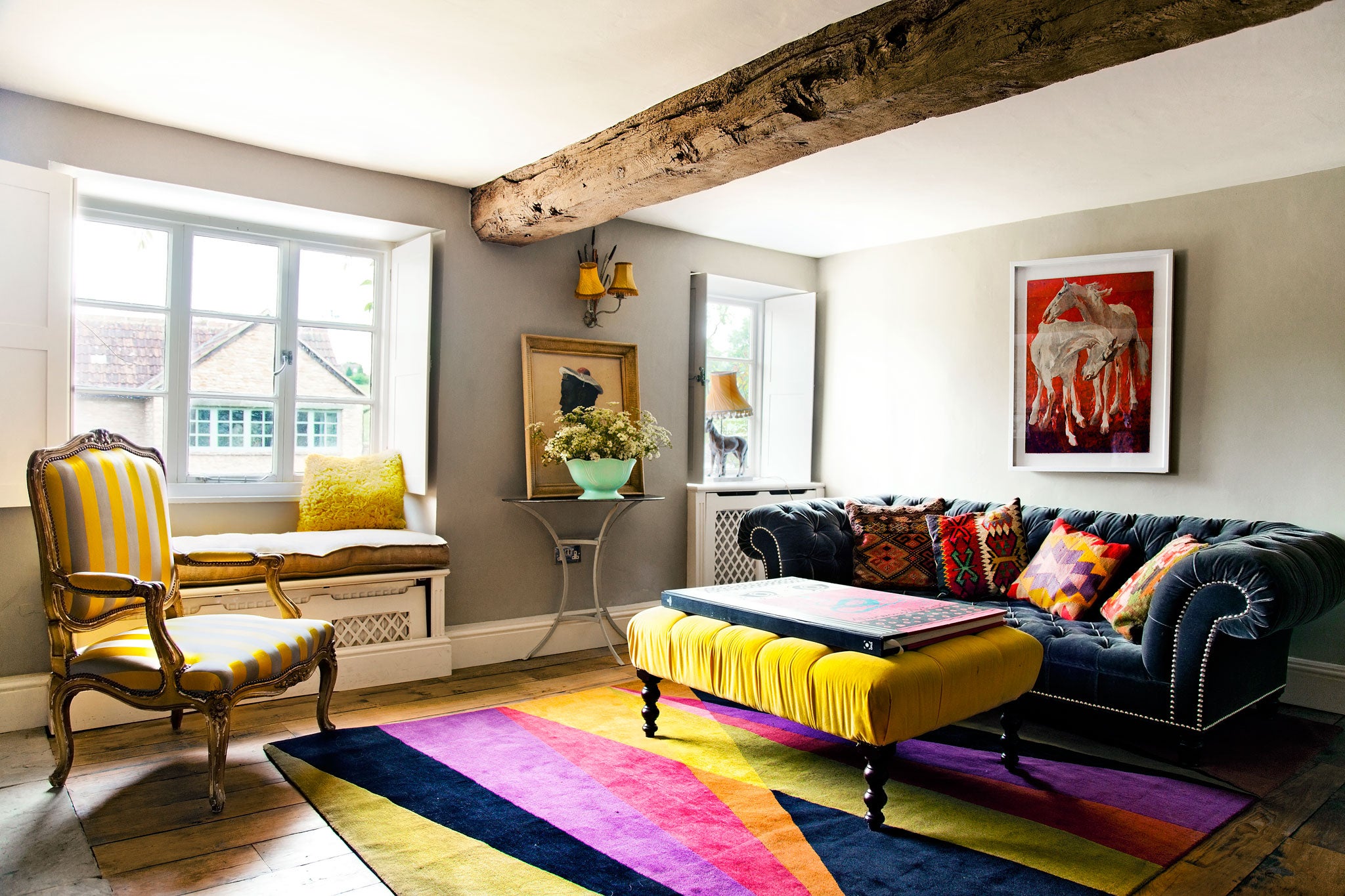 Perfect mismatch: Berryman, who likes her interiors bold, pairs a deep-blue sofa with neon-yellow chairs and bright cushions, and throws in some equine antiques for good measure