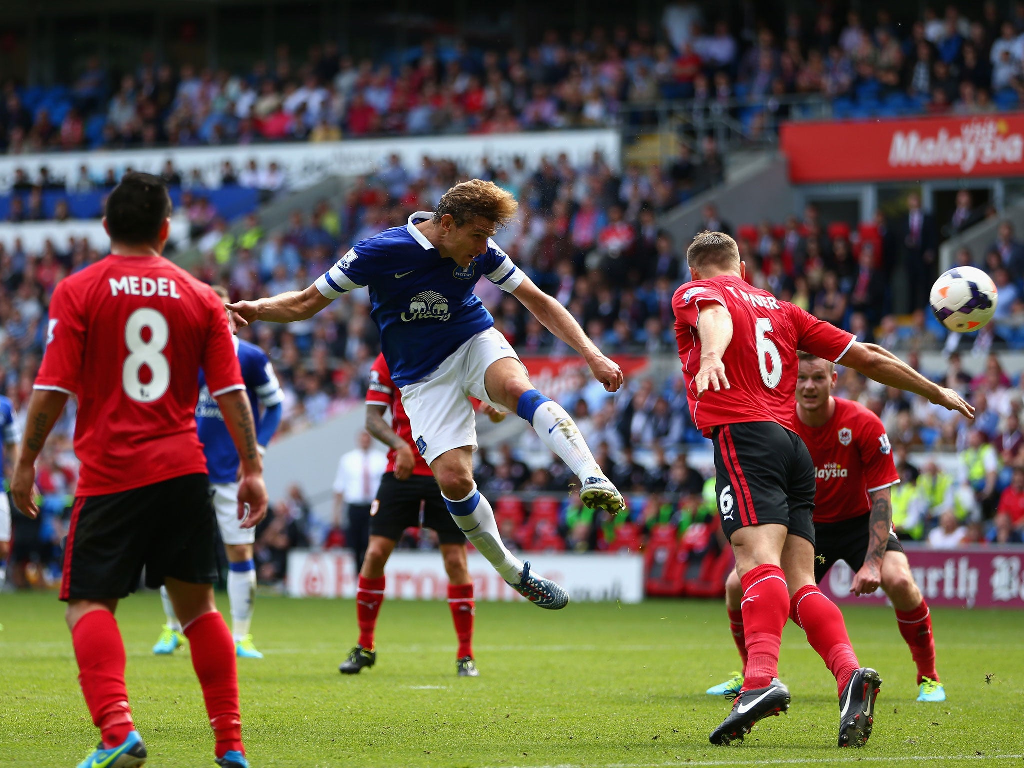 Nikica Jelavic of Everton heads the ball past Ben Turner of Cardiff