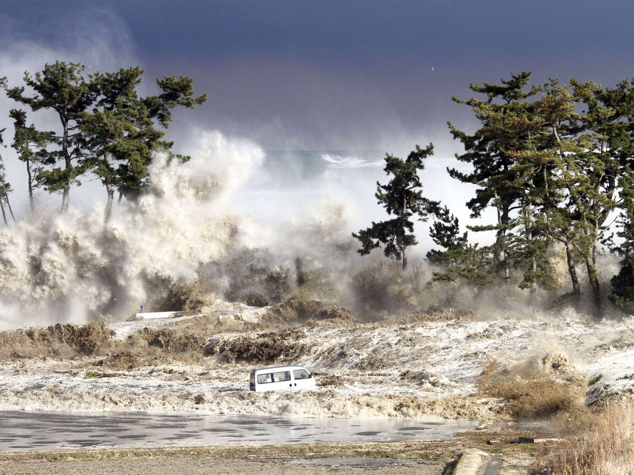 Tsunami waves crash through the coastal city of Minamisoma (Getty)