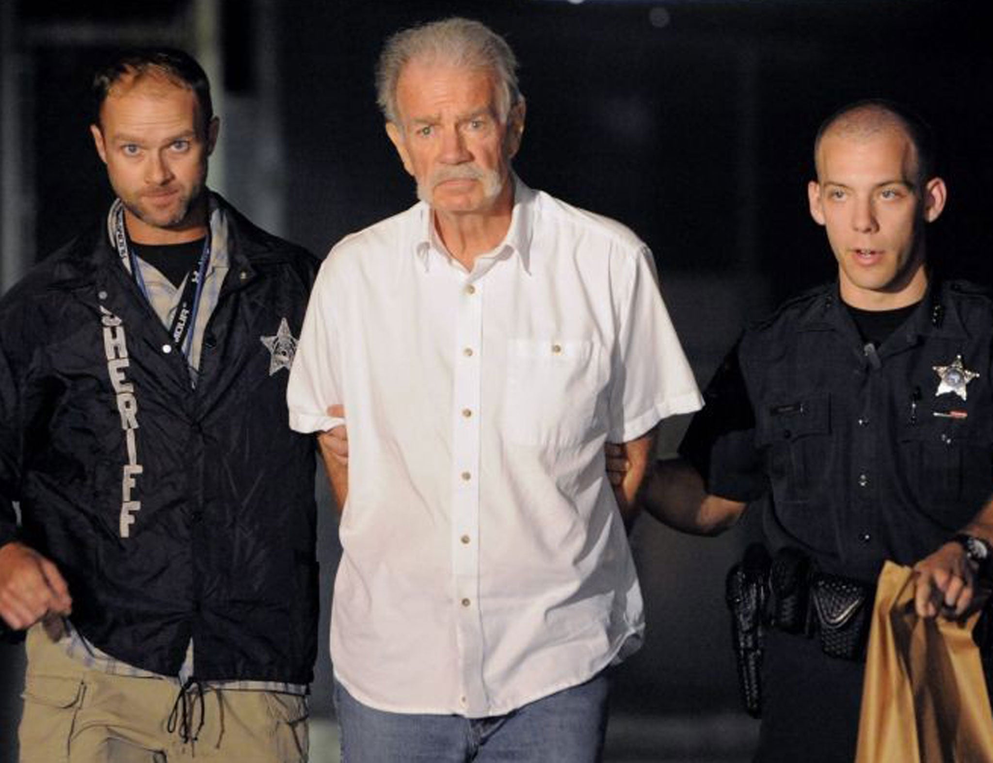 Police officers escort Terry Jones to a waiting patrol car