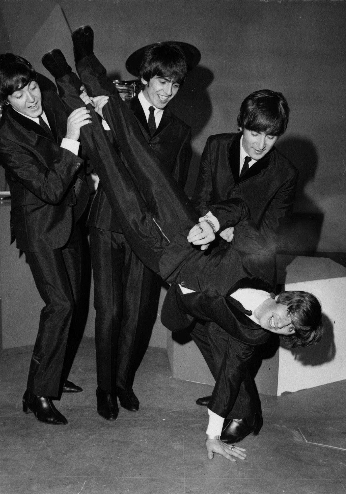 The Beatles in shiny suits at a BBC studio, holding drummer Ringo Starr upside down to give him 'the bumps' the day after his 24th birthday in 1964