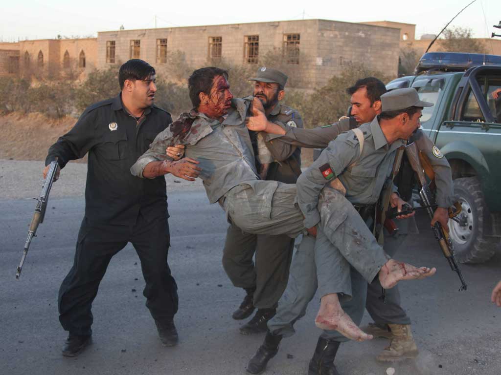 Afghan security personnel assist an injured police after the suicide car bombing and gunfight