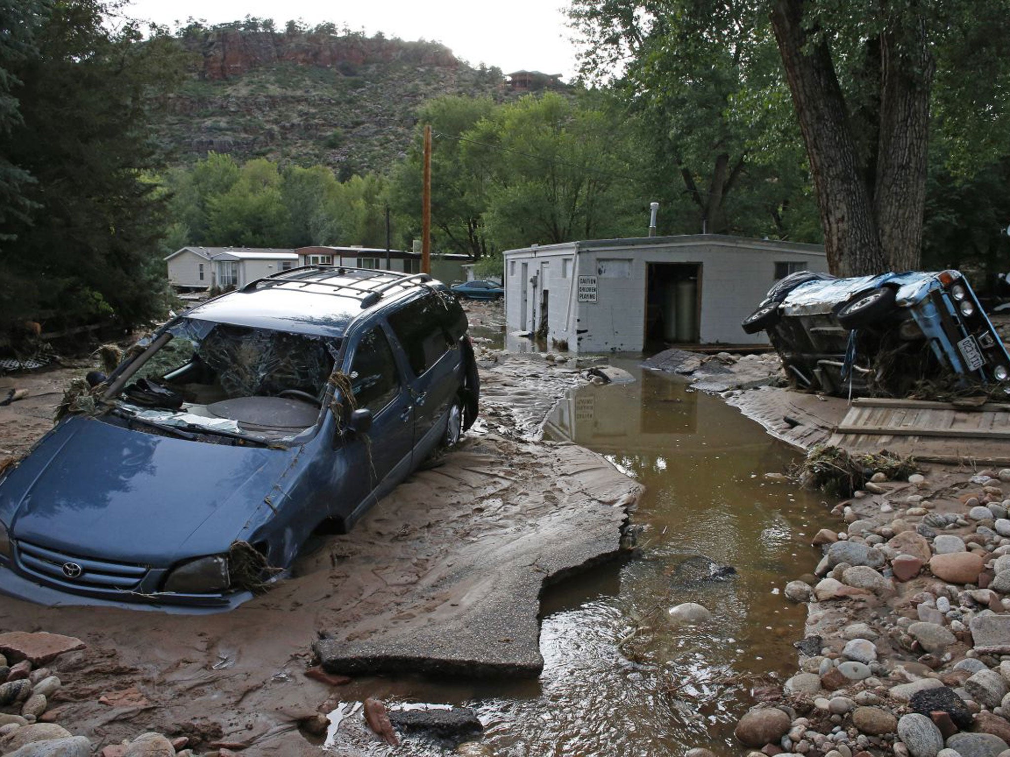 Cars lay mired in mud deposited by floods in Lyons, Colorado