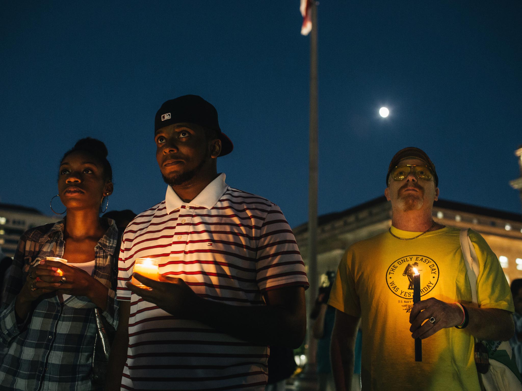 Brittany Carter, of Bowie, MD., (left) Jibri Johnson, of Landon, MD., (centre) and Bryan Beard of Washington D.C. hold candles in remembrance of people affected by gun violence during a vigil at Freedom Plaza