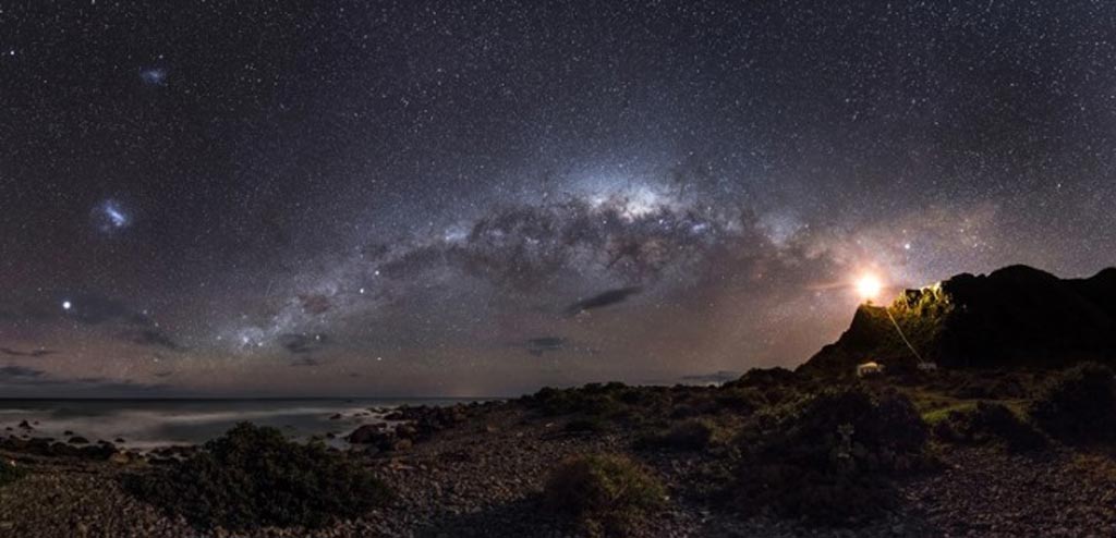 Winner and Overall Winner - Guiding Light to the Stars © Mark Gee (Australia): The skies of the Southern Hemisphere offer a rich variety of astronomical highlights. The central regions of the Milky Way Galaxy, 26,000 light years away, appear as a tangle of dust and stars in the central part of the image. Two even more distant objects are visible as smudges of light in the upper left of the picture. These are the Magellanic Clouds, two small satellite galaxies in orbit around the Milky Way.