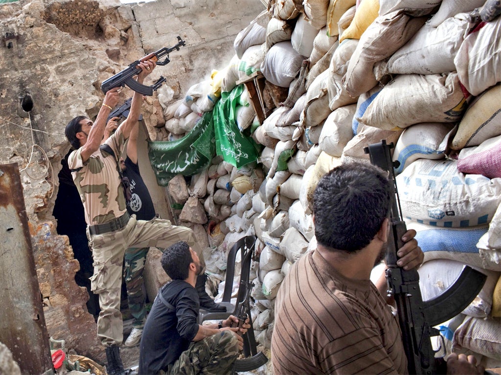 Rebel fighters shoot over a barricade in Aleppo (Getty)