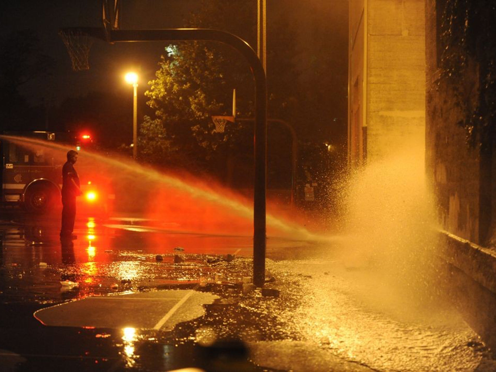 Firefighters turn their hoses on the basketball court to clean away blood