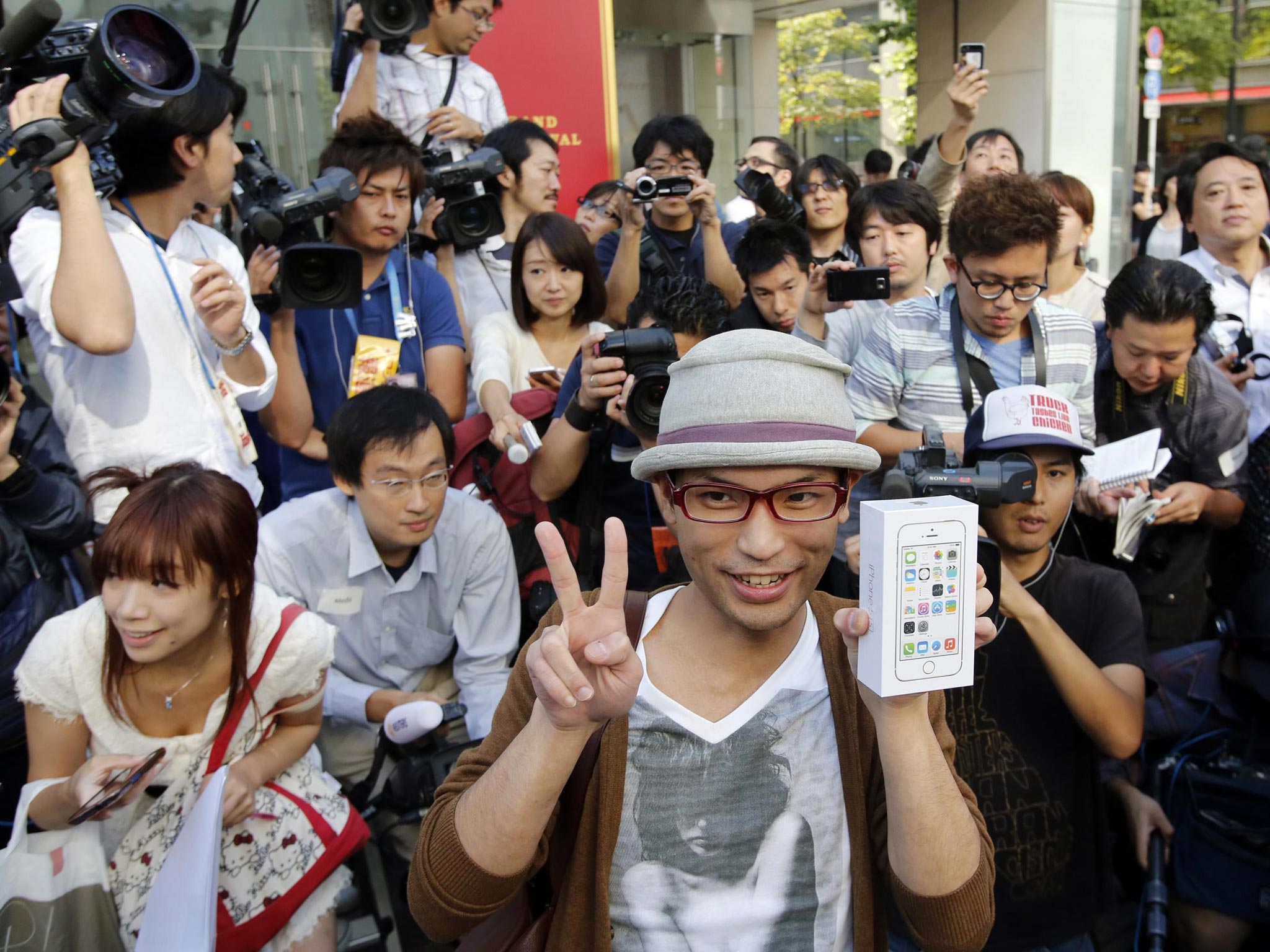 A man poses with a box of the new Apple iPhone 5S for the media after he waited for it since September 10 outside an Apple Store at Tokyo's Ginza shopping district in Japan