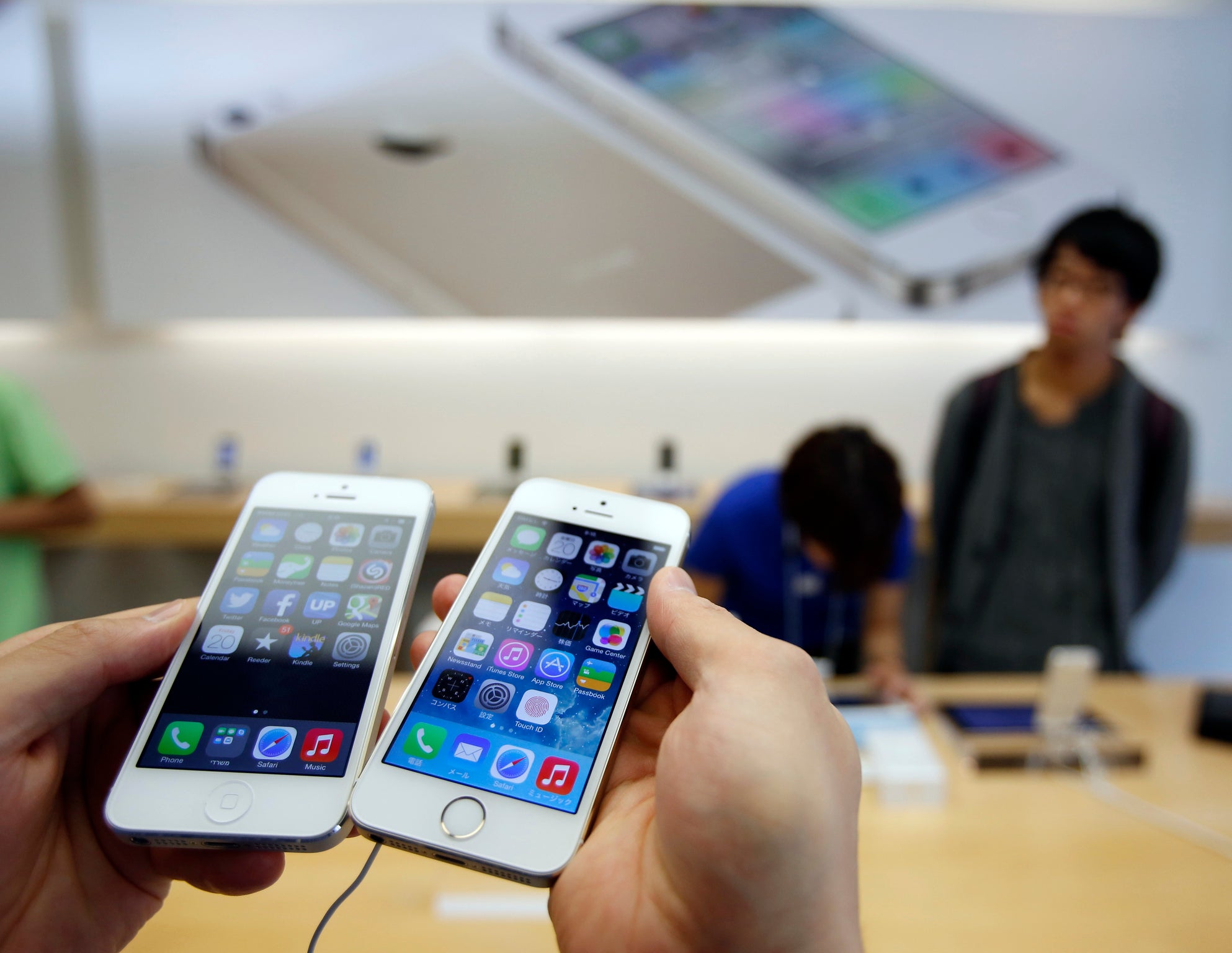 A man holds a new Apple iPhone 5S (R) next to his iPhone 5 at an Apple Store at Tokyo's Ginza shopping district September 20, 2013.