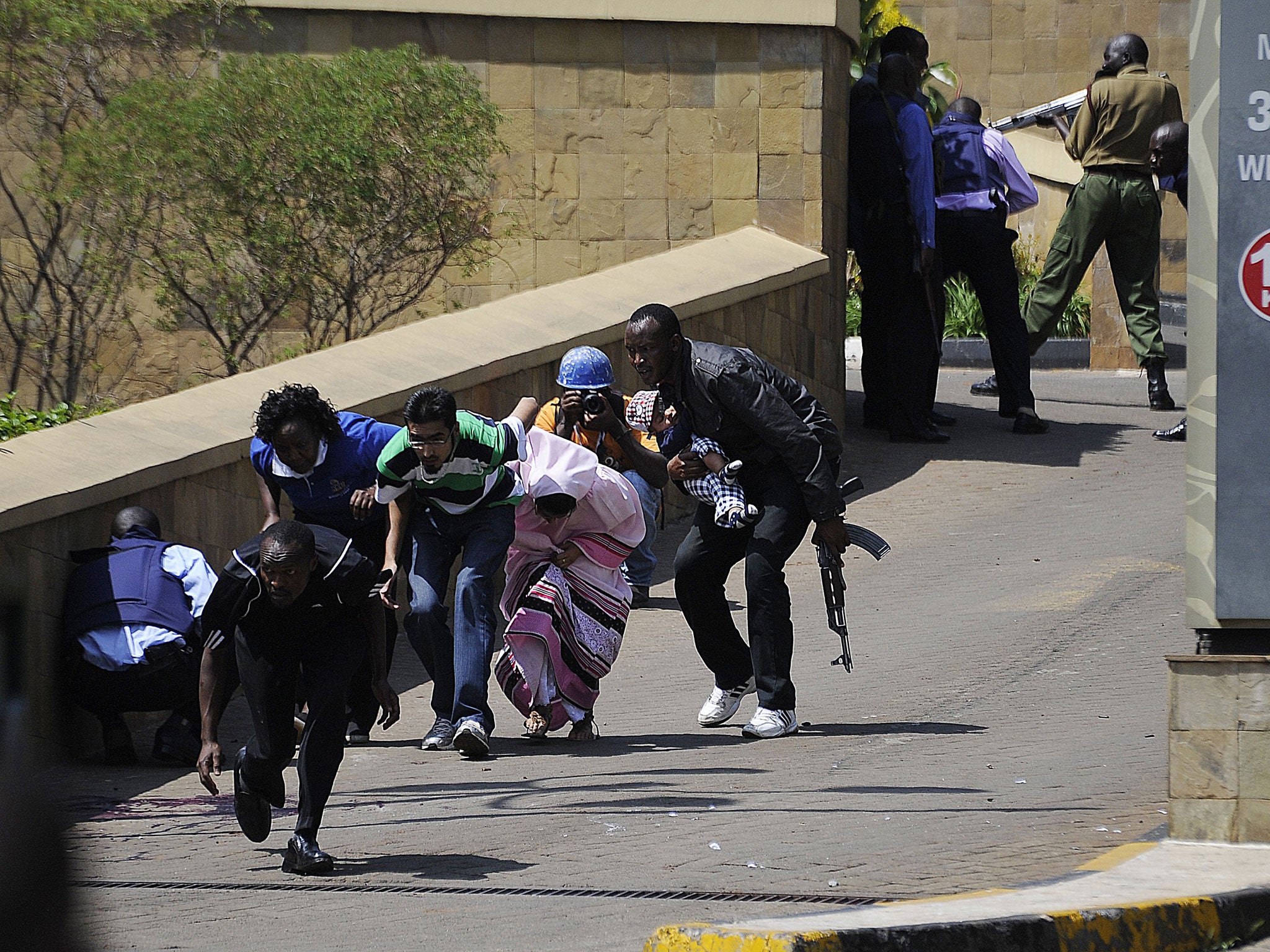 A police officer hurries survivors out of the mall