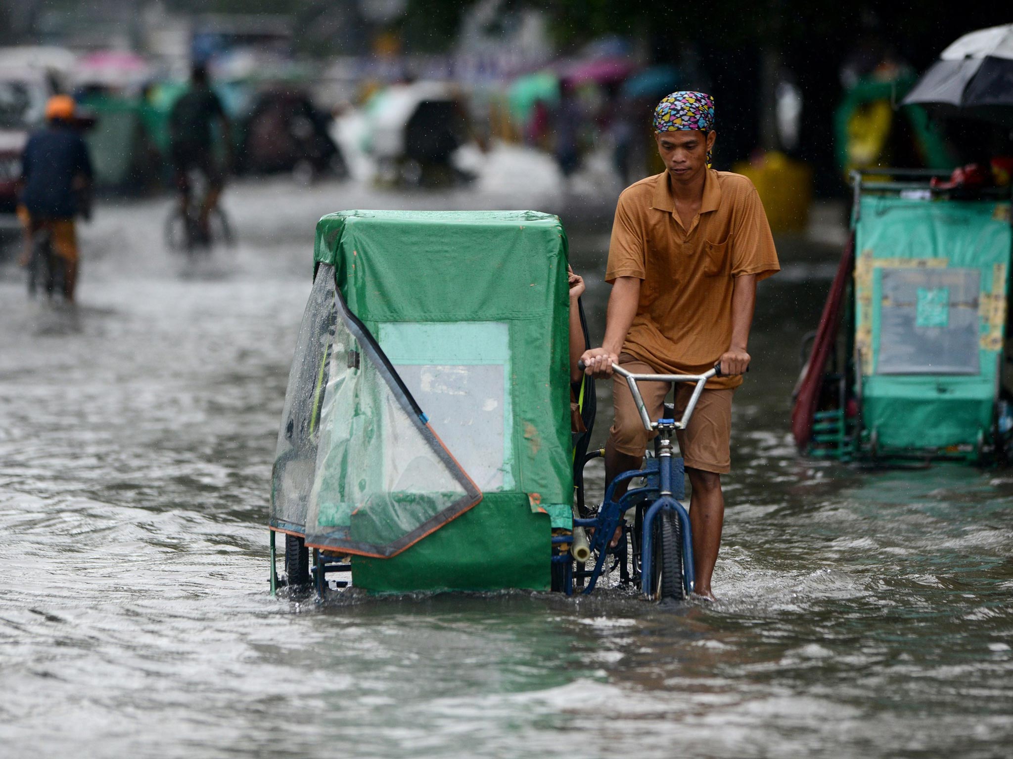 A pedicab driver wades through a flooded street in Manila. Monsoon rains worsened by Typhoon Usagi pounded the Philippines for the third day
