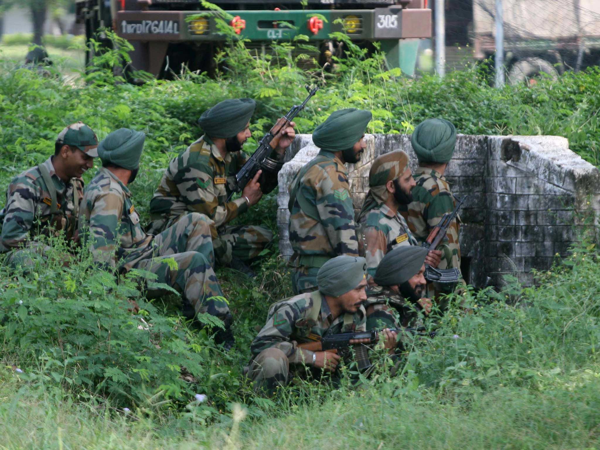 Indian army soldiers gather behind a small wall during an attack by militants on an army camp at Mesar, Samba