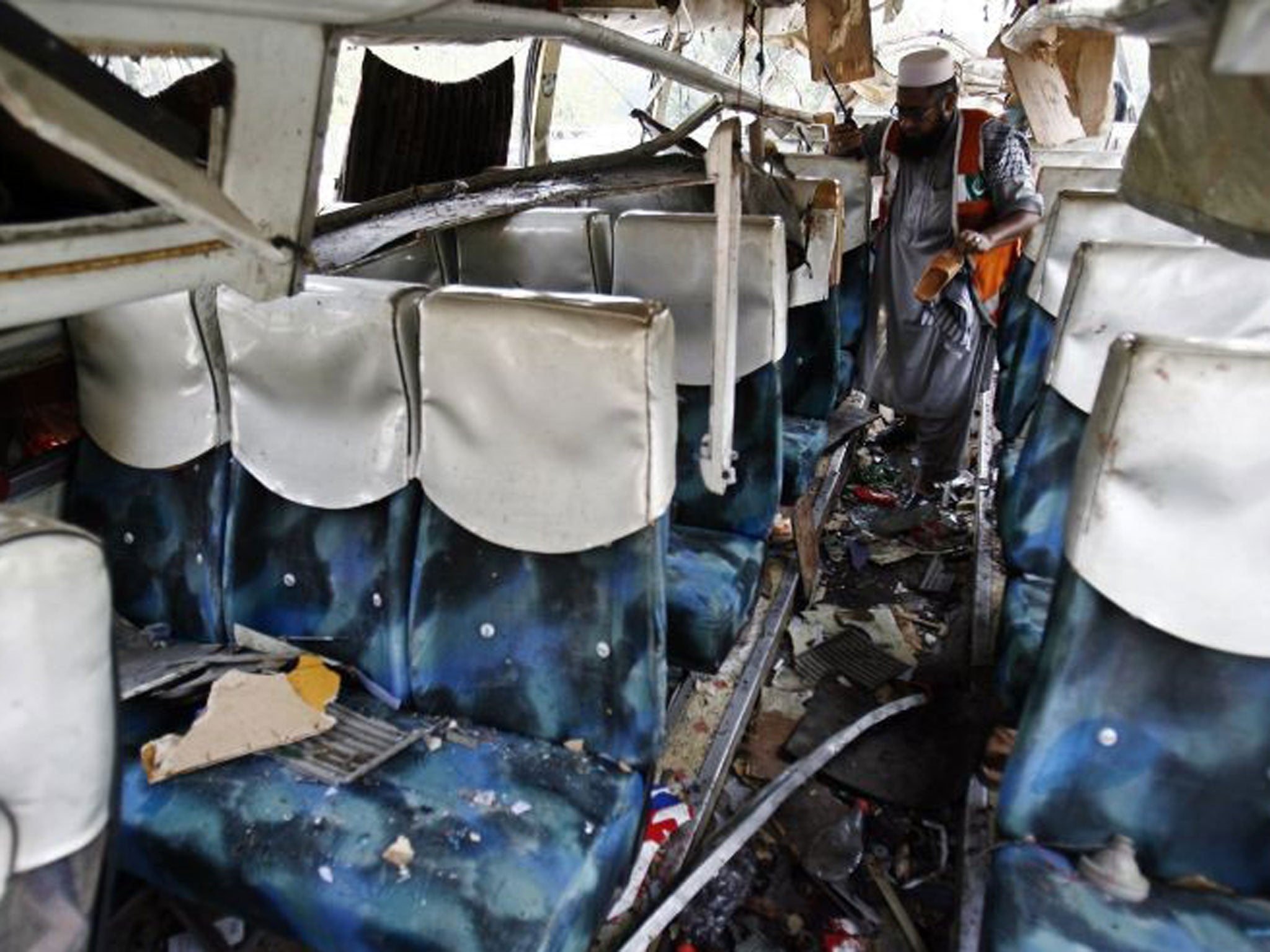 A rescue worker collects evidence from a damaged bus after it was hit by a bomb attack on the outskirts of Peshawar September 27, 2013. A bomb exploded on a bus carrying government officials in the insurgency-plagued Pakistani city of Peshawar on Friday, killing at least 17 people, including two women, officials said.