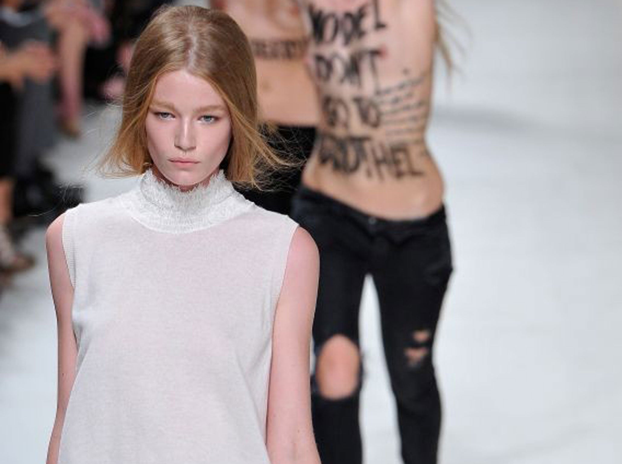 Hollie-May Saker walks the runway as activists of the Ukranian feminist protest group 'Femen' invade the runway at the Nina Ricci show during Paris Fashion Week