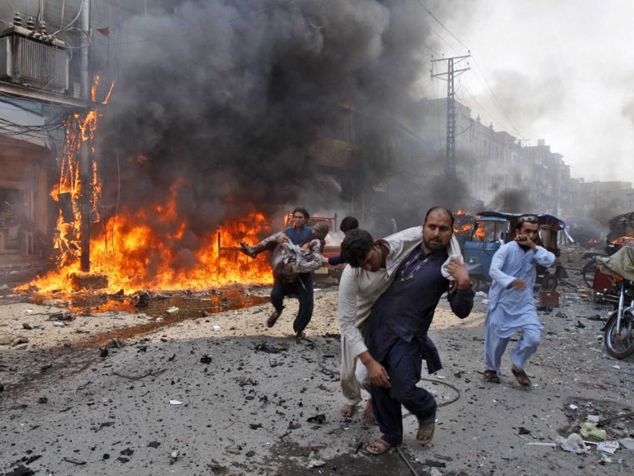 Injured Pakistani men are carried away from the site of a blast shortly after a car explosion in Peshawar, 29 September