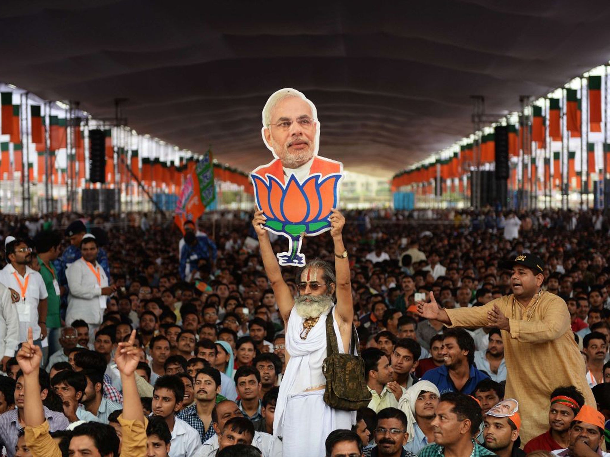 A supporter of the BJP holds a cutout of Narendra Modi during the election rally in New Delhi