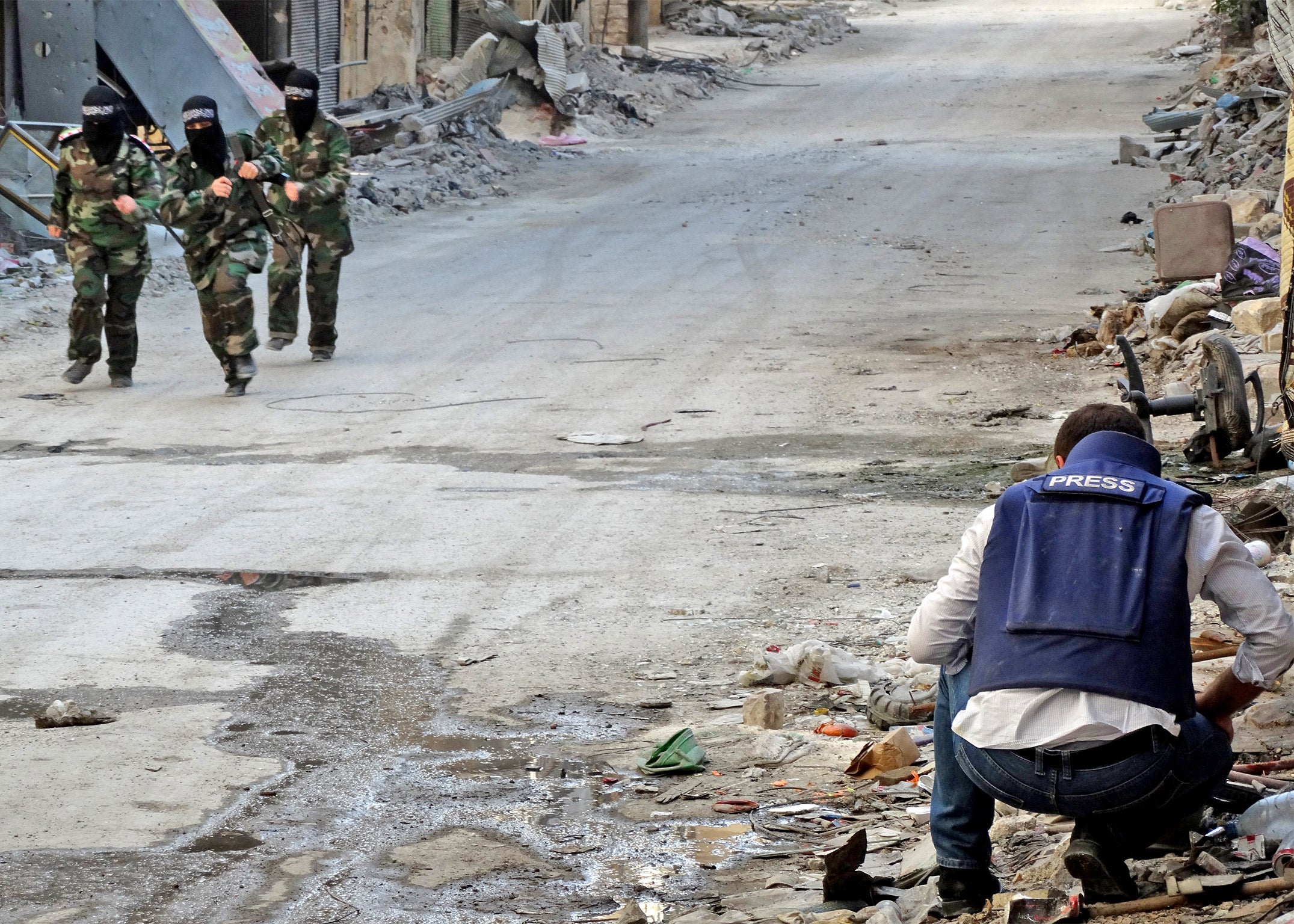 Masked rebel fighters run past a journalist in the Salaheddin district of Aleppo last week