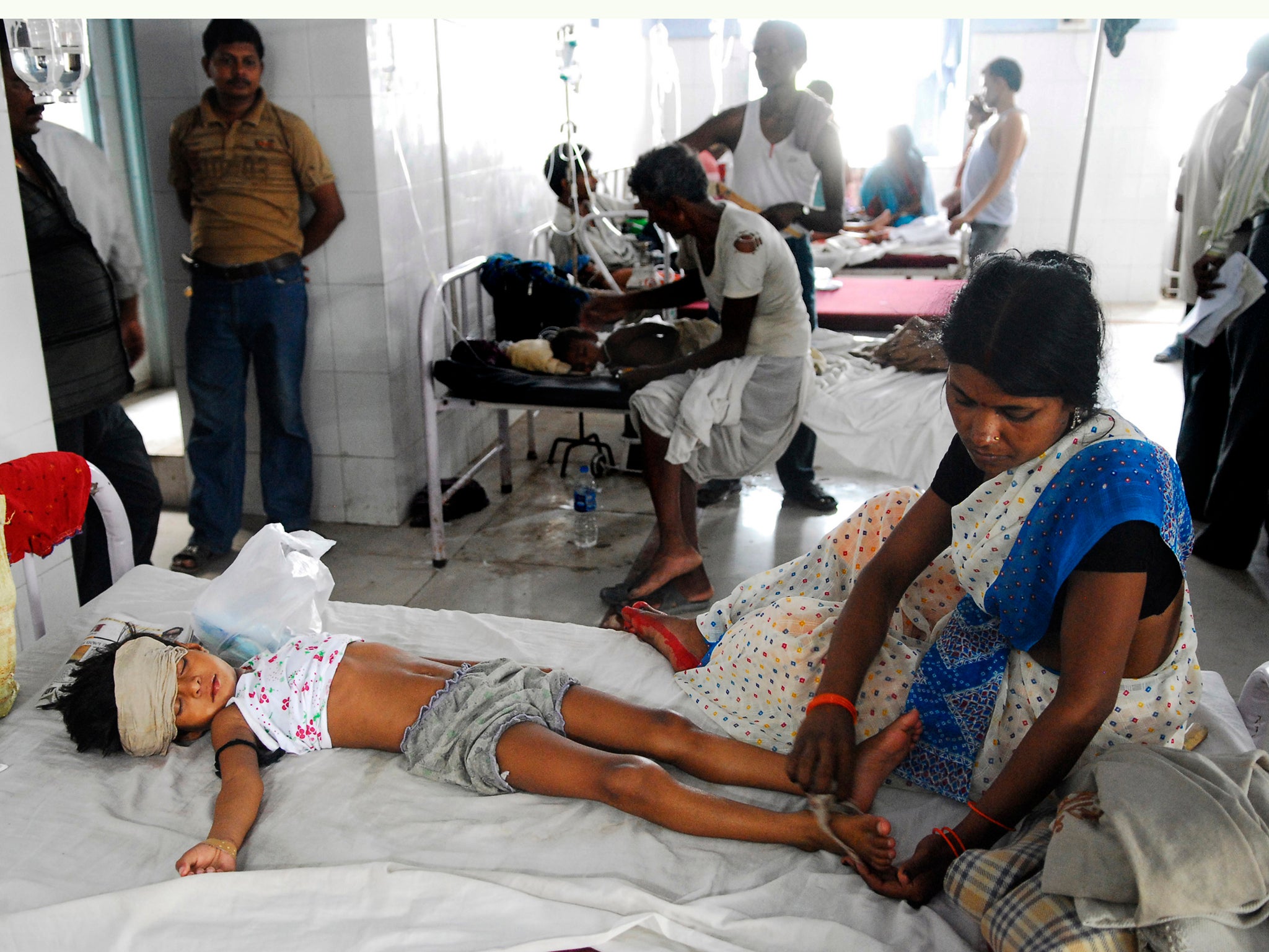 An Indian woman attends to a child lying in a bed in hospital. Health officials are battling to confront a new outbreak of encephalitis, a disease that has this year killed at least 350 children in one state alone