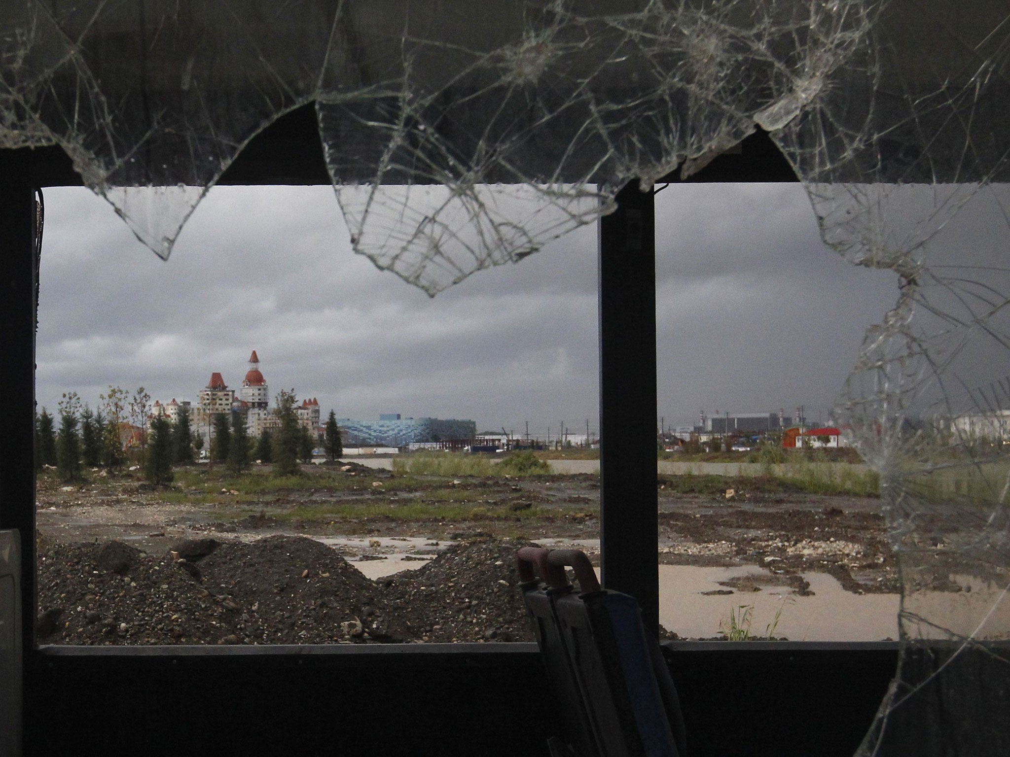 A view of Olympic venues and accommodation complex is seen through the window of an abandoned bus in the Adler district of Sochi