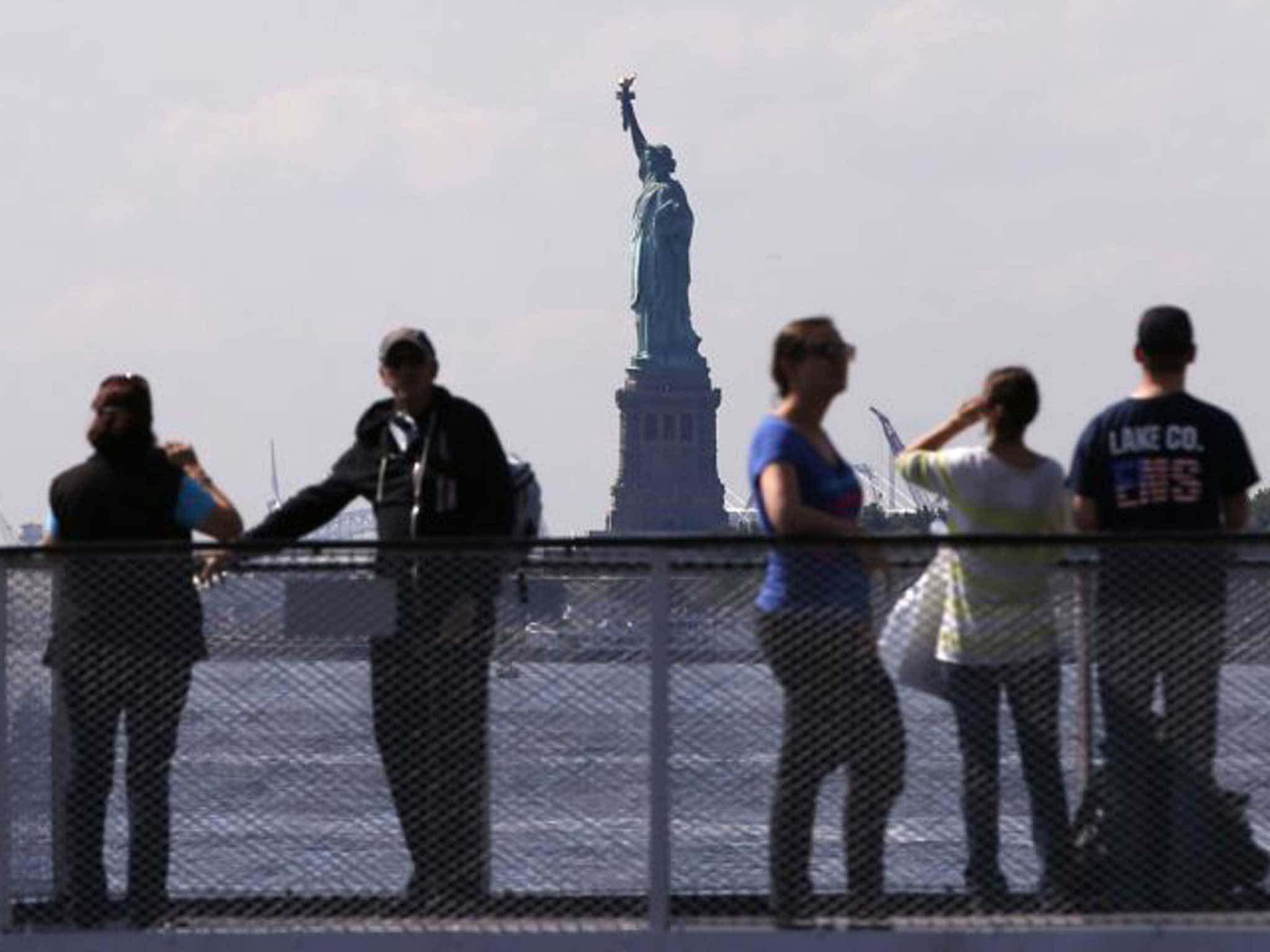 Tourists pause to view the Statue of Liberty from the deck of a Liberty Island ferry boat at Battery Park in New York