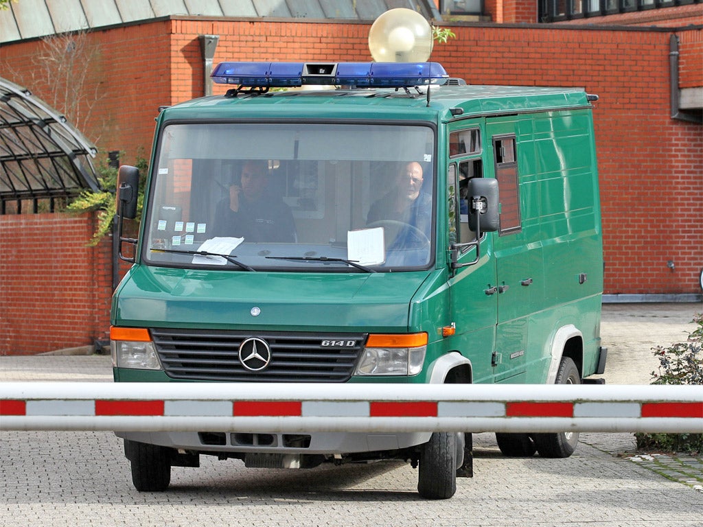 A van transports Hassan and his alleged accomplice to prison