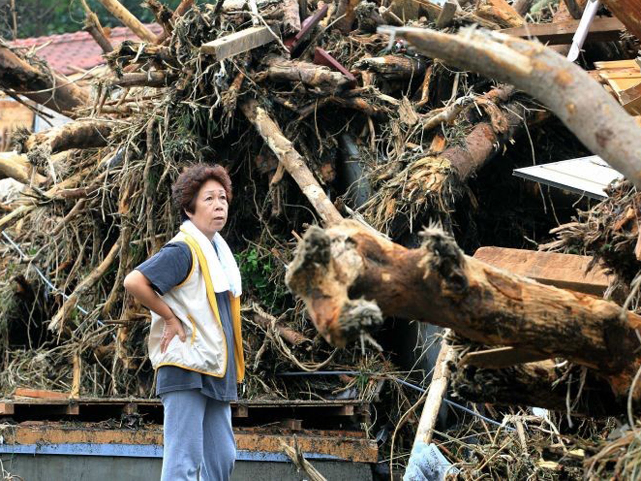 A woman reacts in front of collapsed houses following a landslide caused by Typhoon Wipha on Izu Oshima island